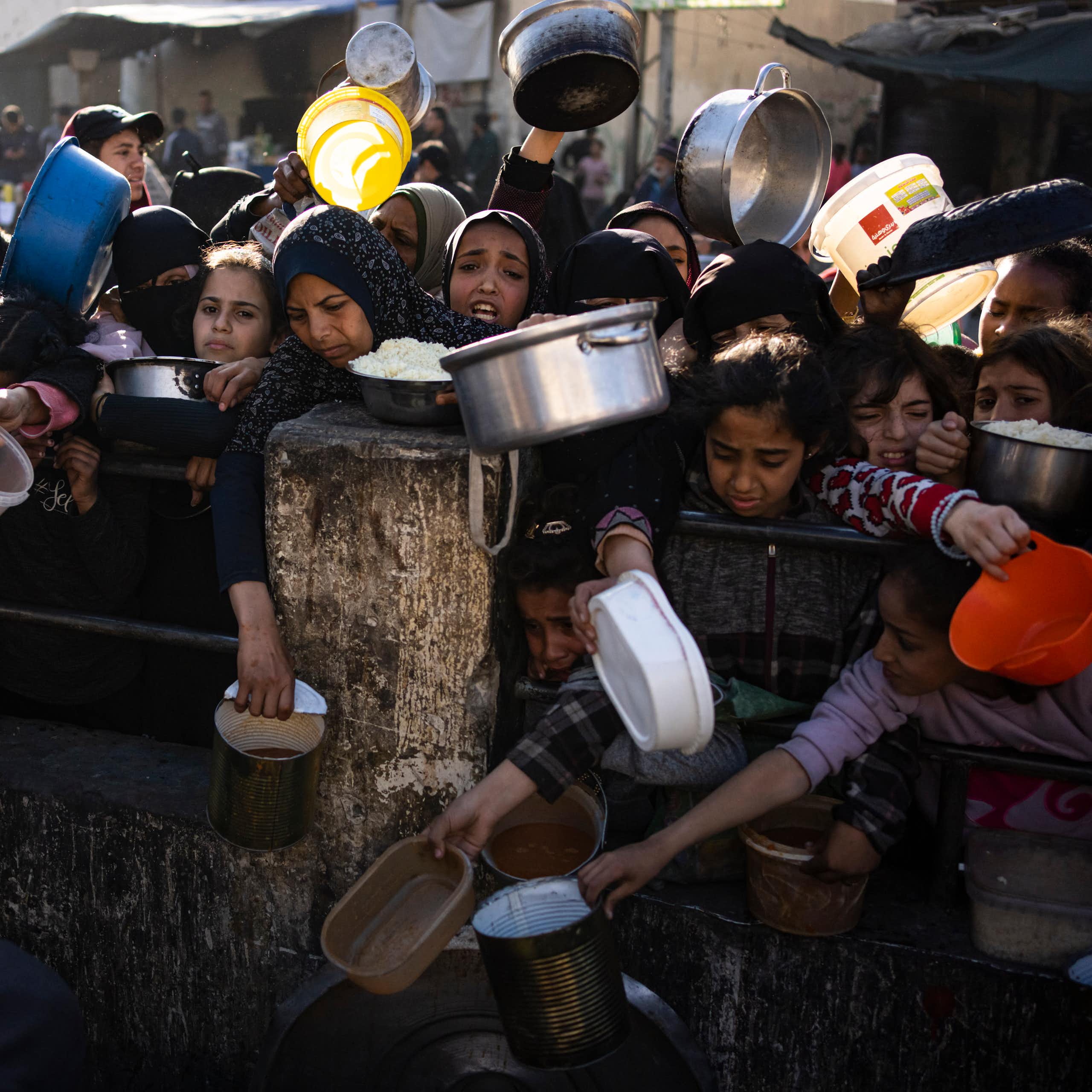 a group of people hold out metal pots