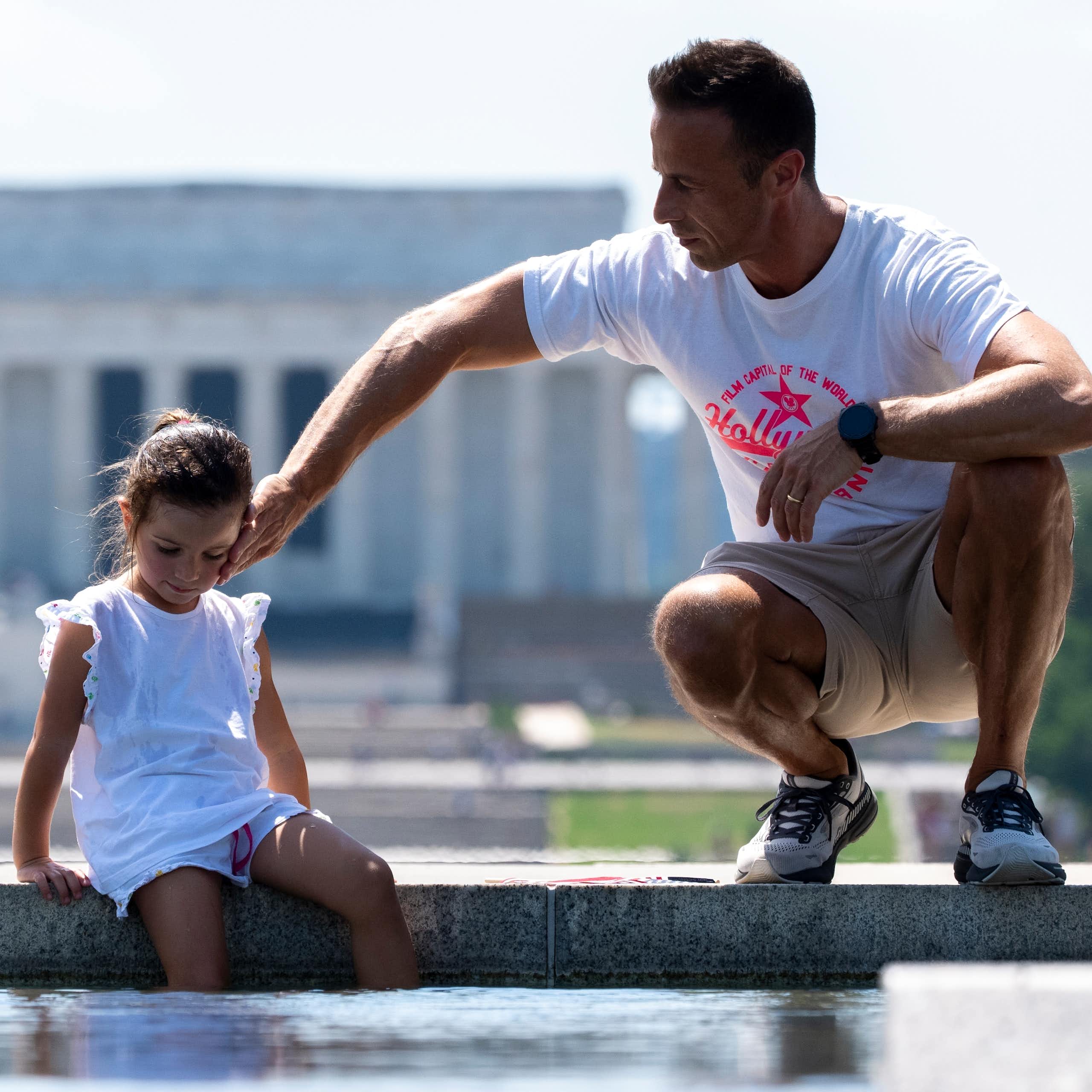 A man and a young girl are pictured in front of a monument.