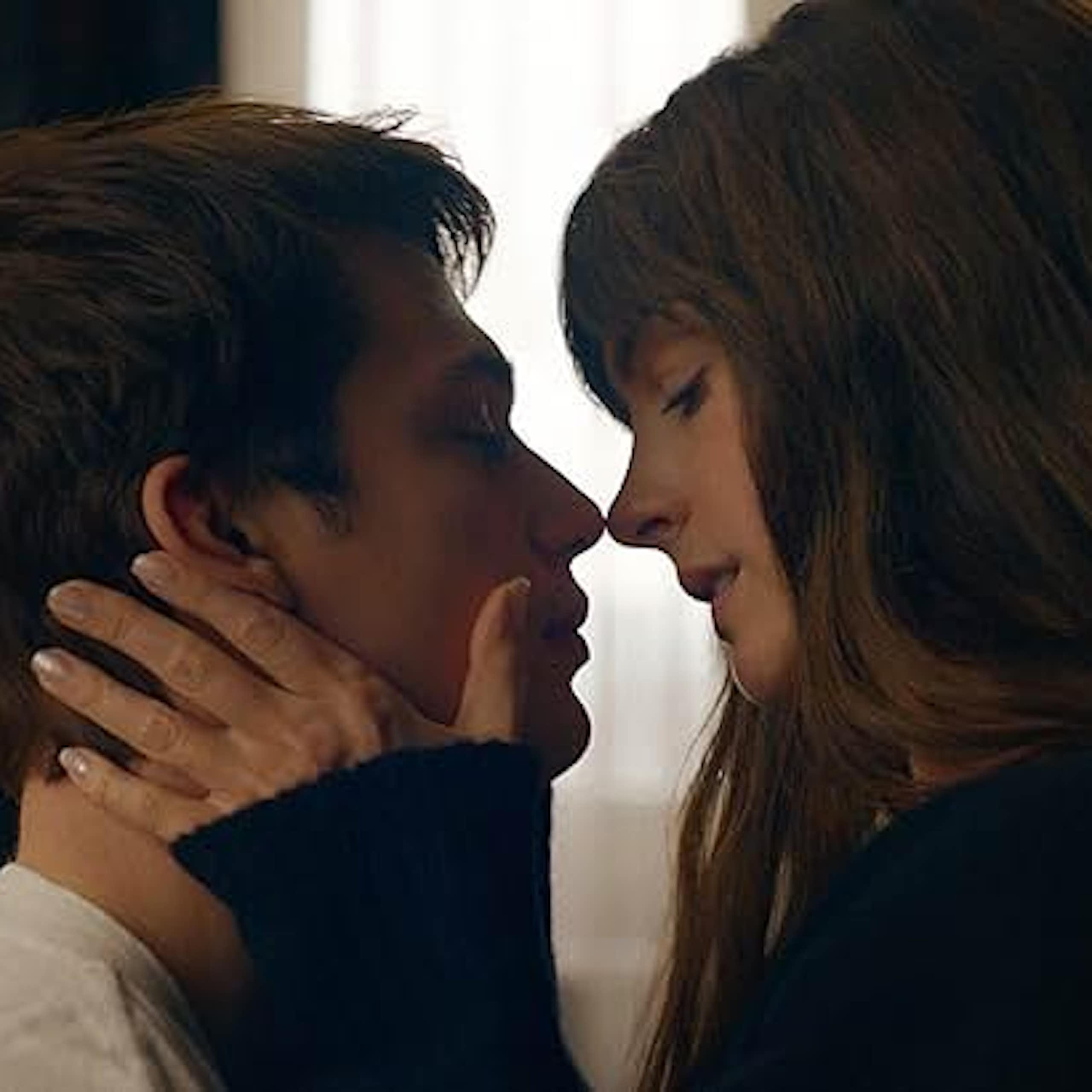 A man and woman embrace and lean in for a kiss