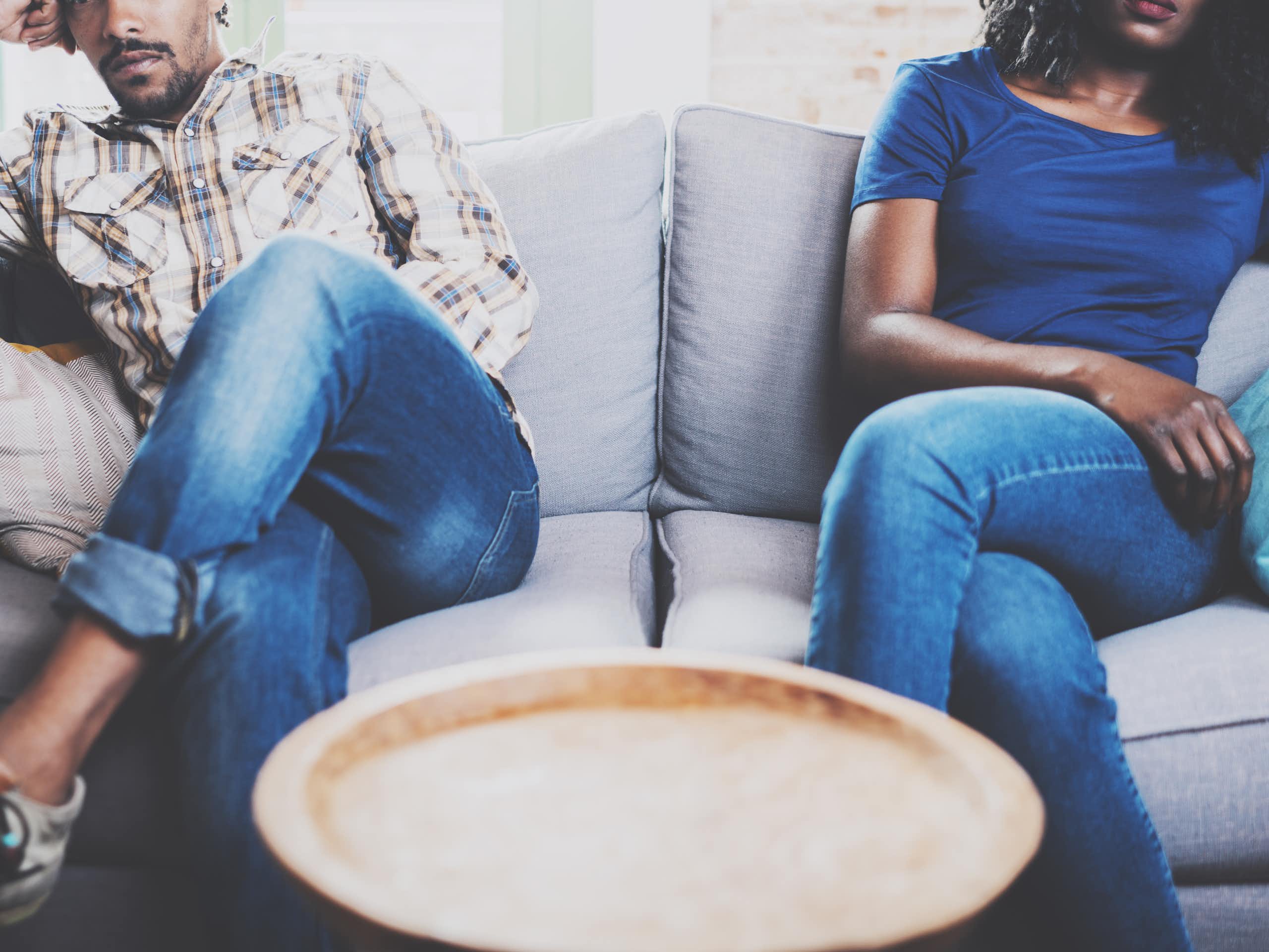 Two people sit apart from each other on a couch