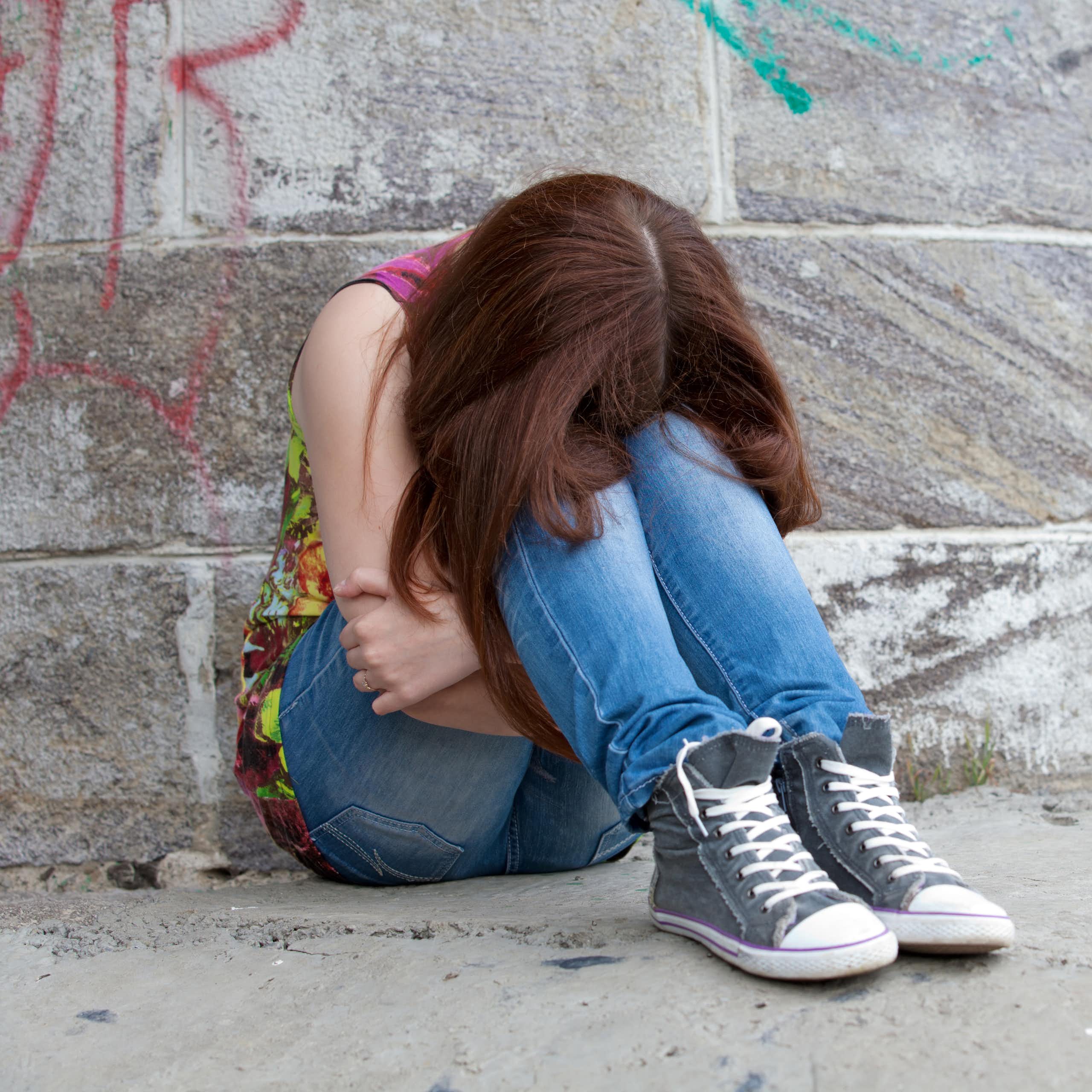 Une adolescente recroquevillée assise sur le sol