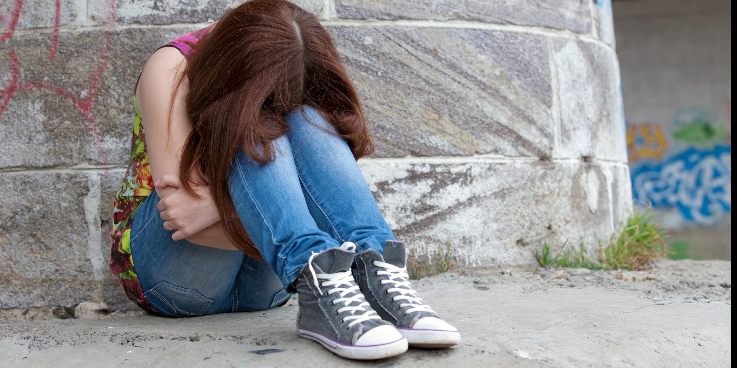 Une adolescente recroquevillée assise sur le sol