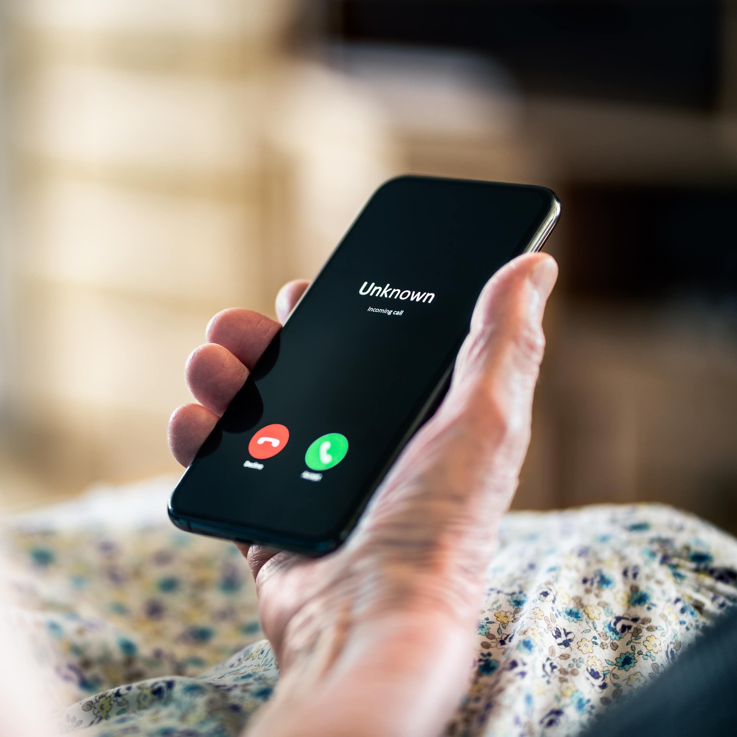 La main d'une personne âgée tient un téléphone cellulaire. 