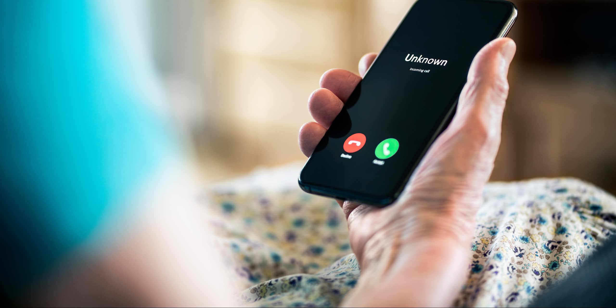 La main d'une personne âgée tient un téléphone cellulaire. 