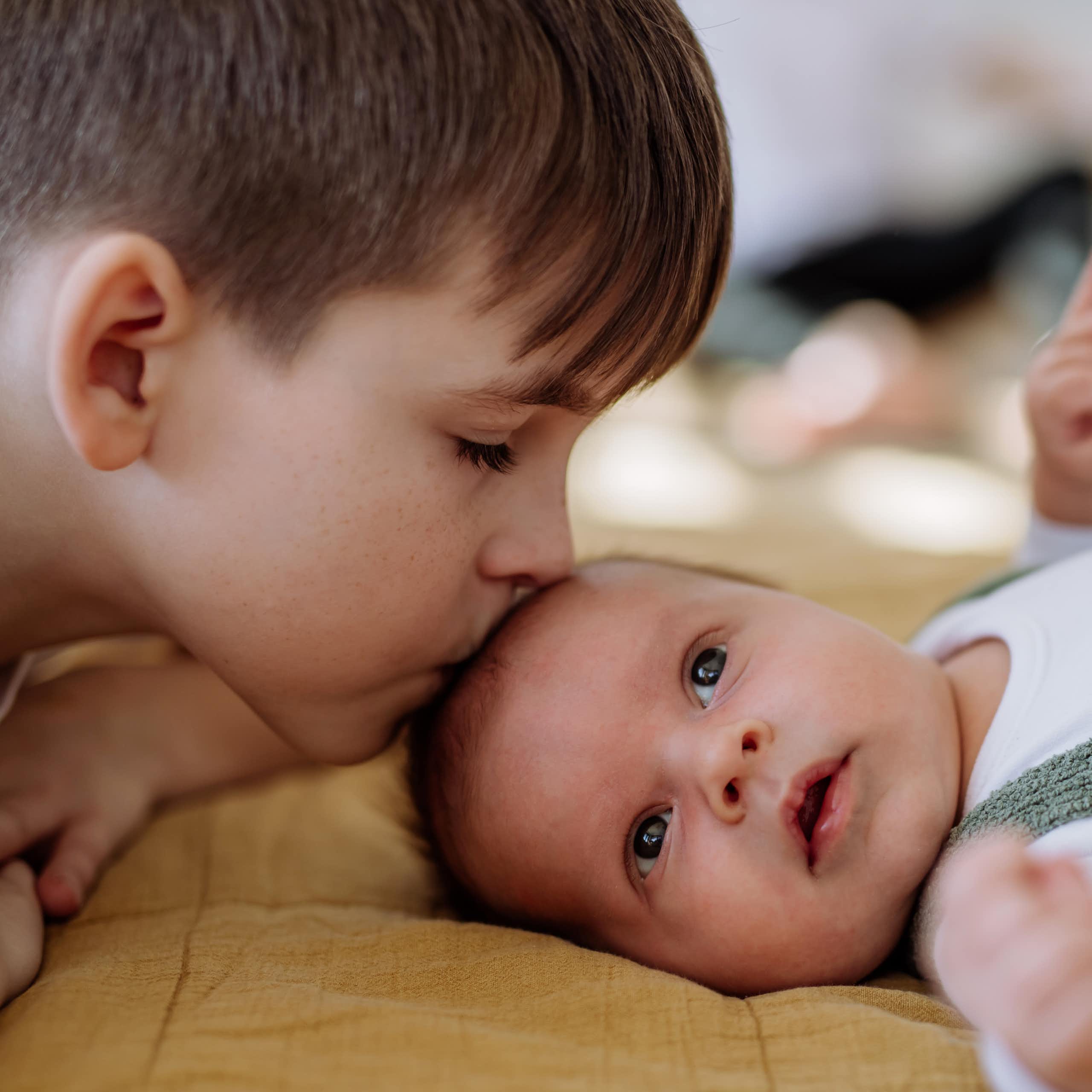 A boy kissing a little baby.