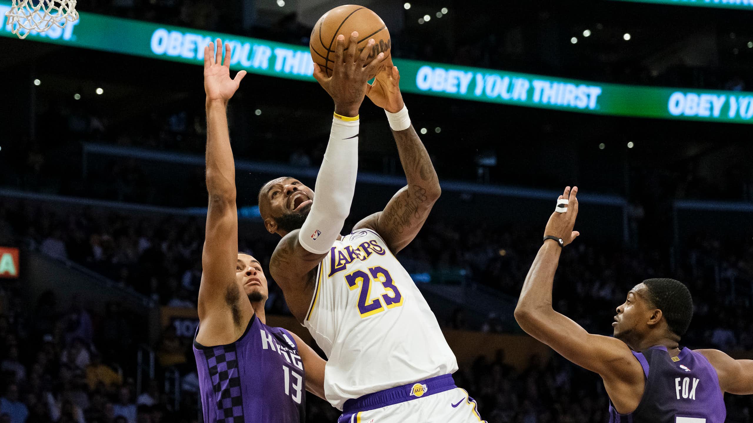 Un homme tient un ballon de basketball et tente de marquer un point.
