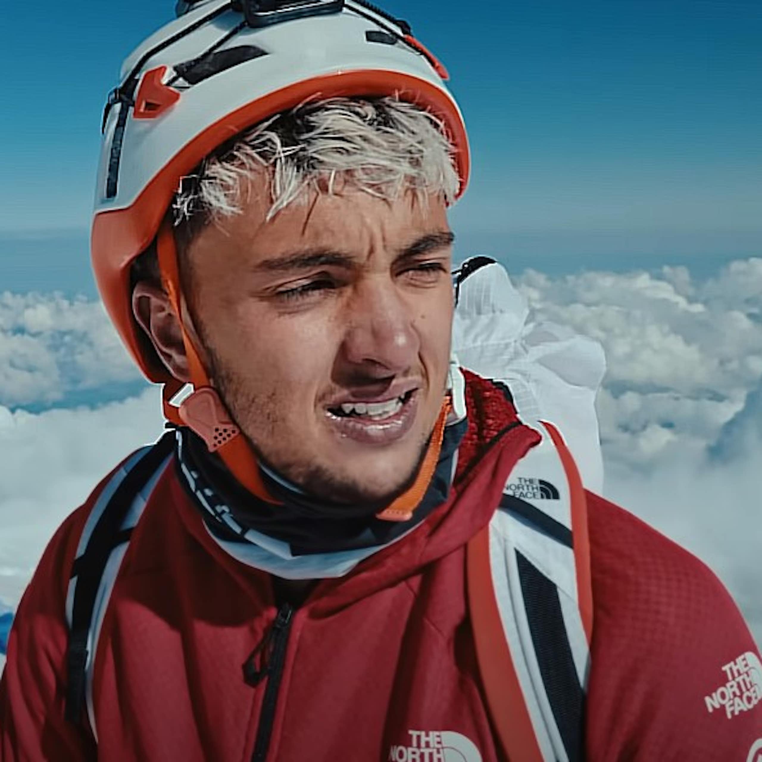 Un homme en tenue d'alpinisme se trouve en haute altitude.