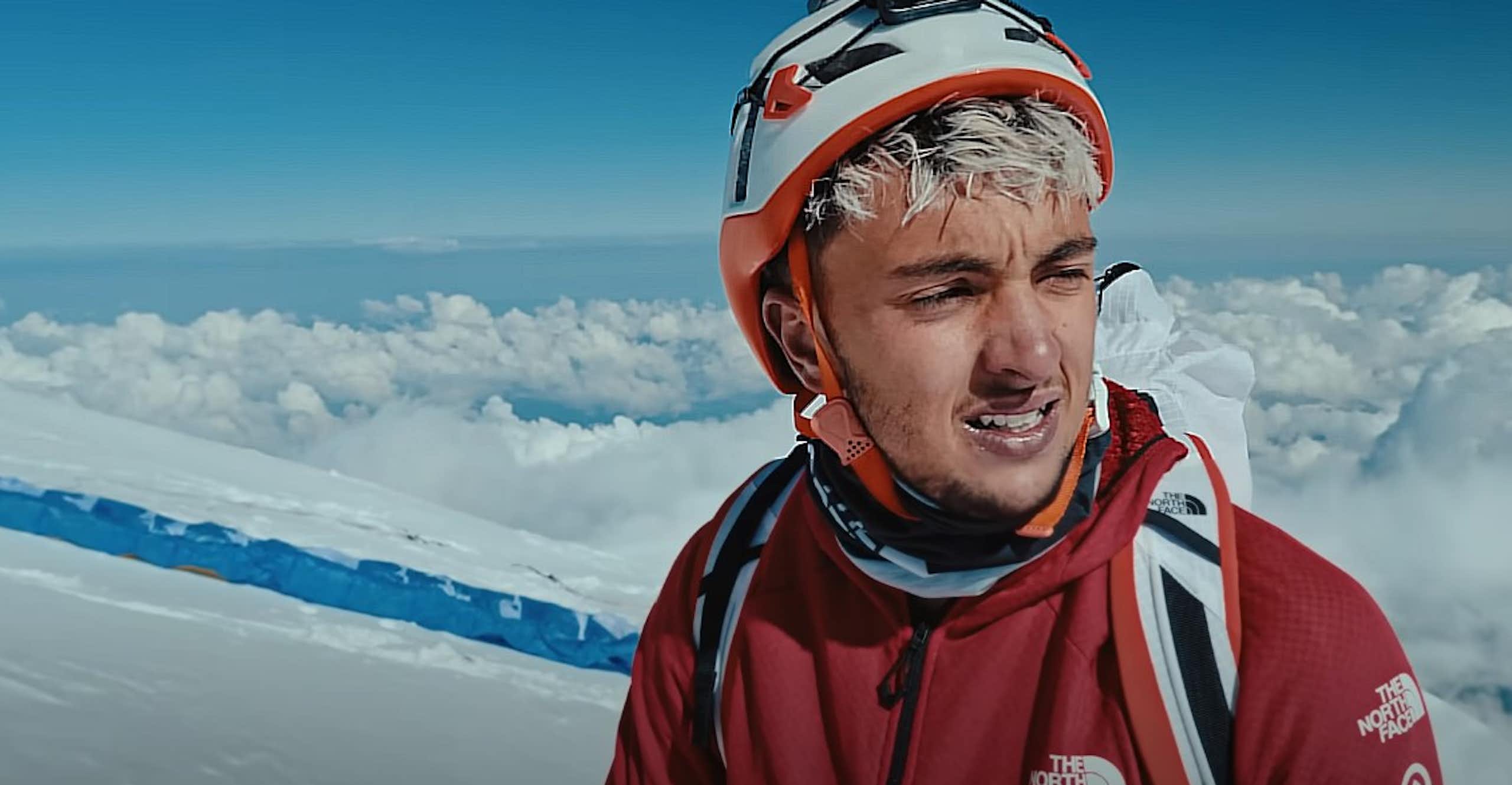 Un homme en tenue d'alpinisme se trouve en haute altitude.