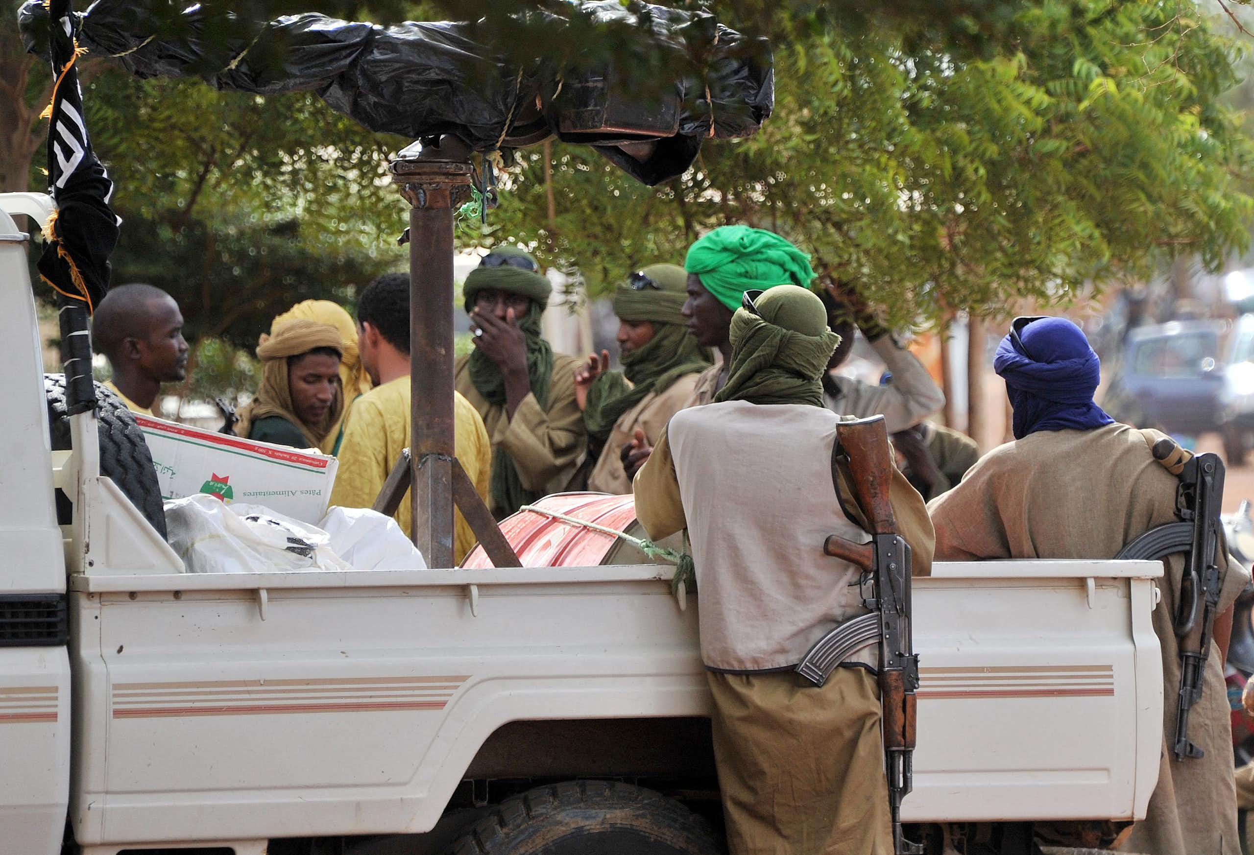 Men holding rifles, gathered around a pick up truck.