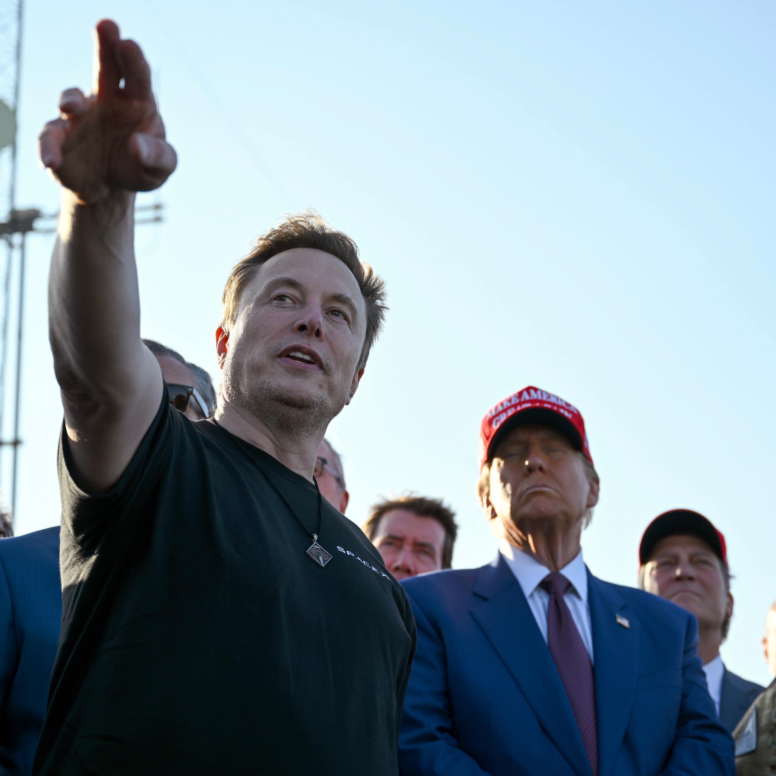 Un homme entouré d'autres hommes pointe l'horizon.