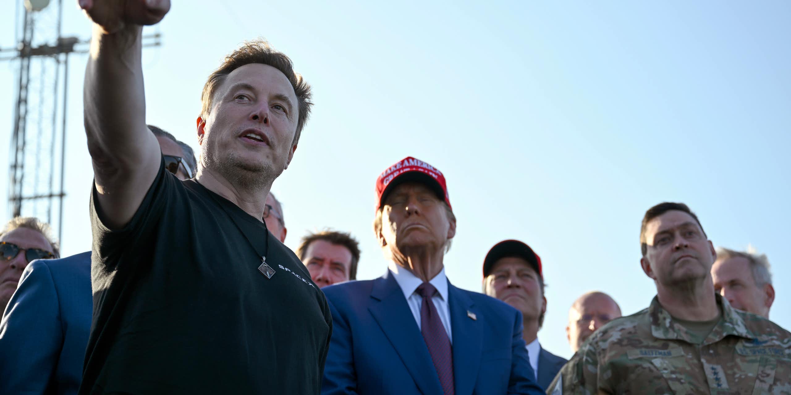 Un homme entouré d'autres hommes pointe l'horizon.