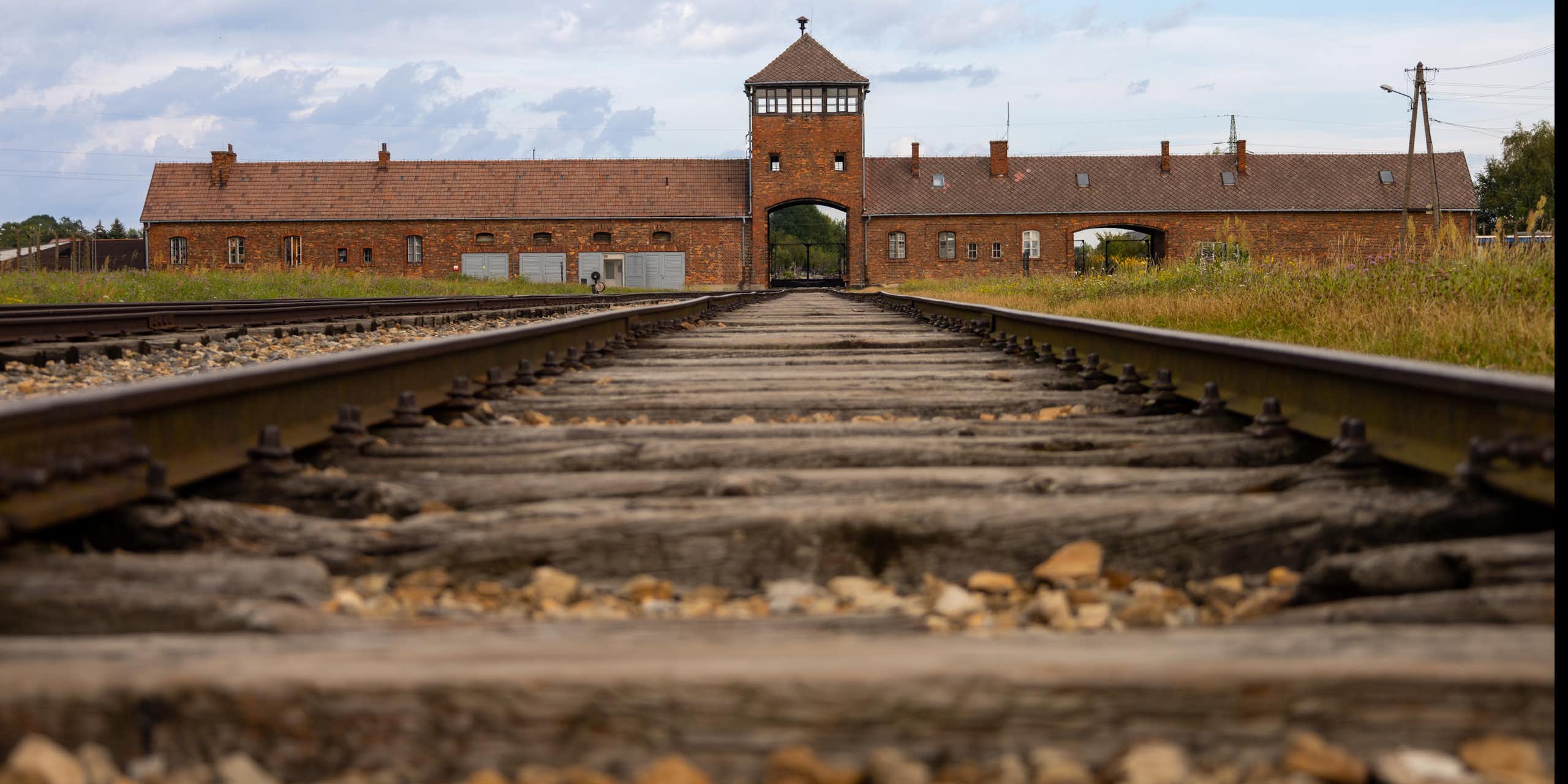 Vue sur une voie ferrée désaffectée, menant à un bâtiment en brique.
