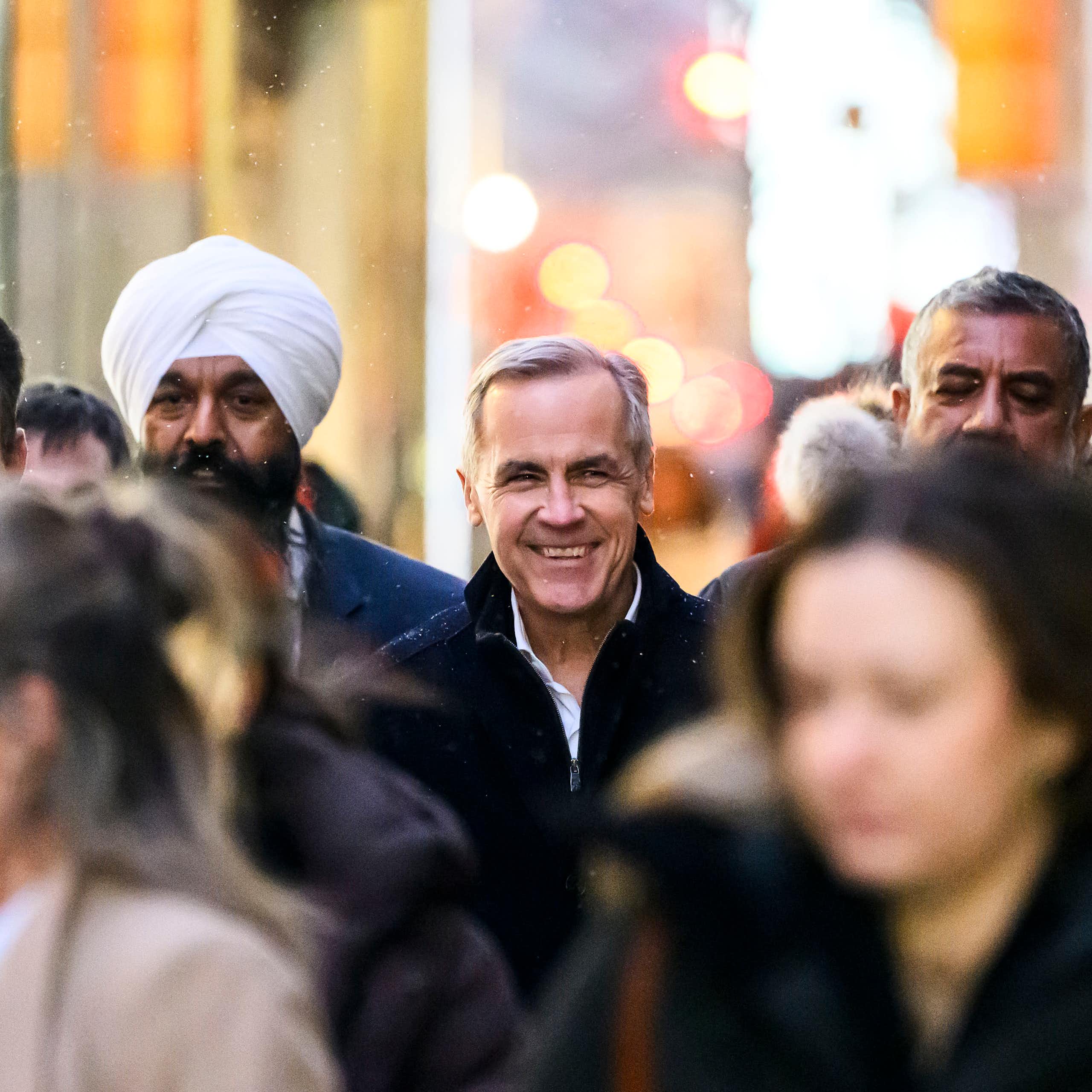 A smiling man in the midst of several people in blurred focus.
