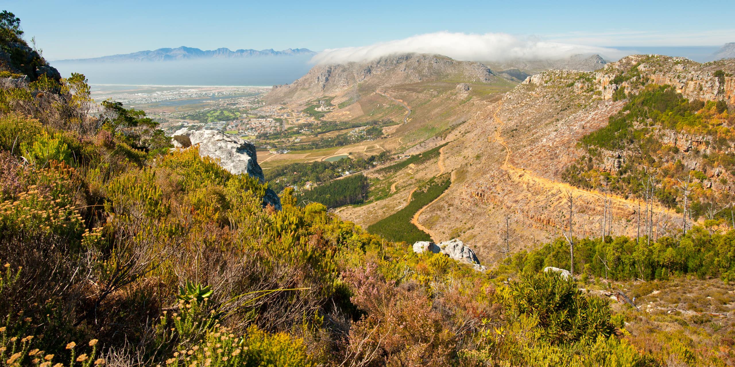 View from a mountain top, looking down to a city and away to distant mountains