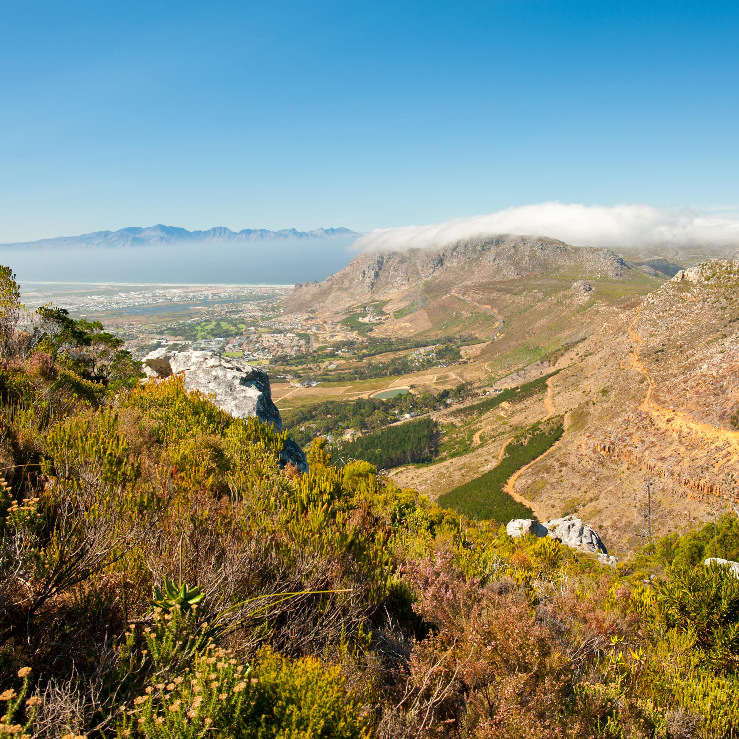 View from a mountain top, looking down to a city and away to distant mountains