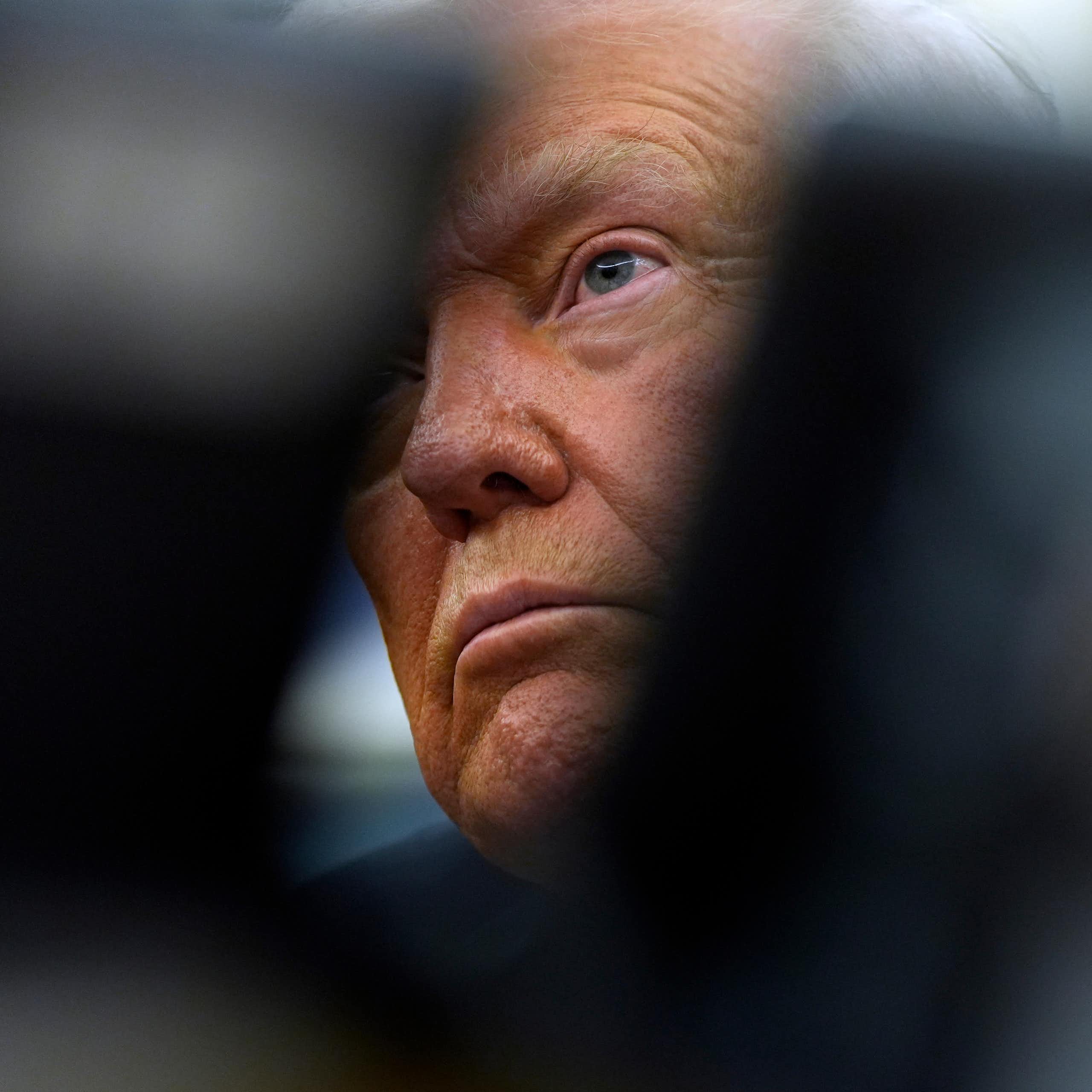 An elderly man's tanned face is partially obscured.