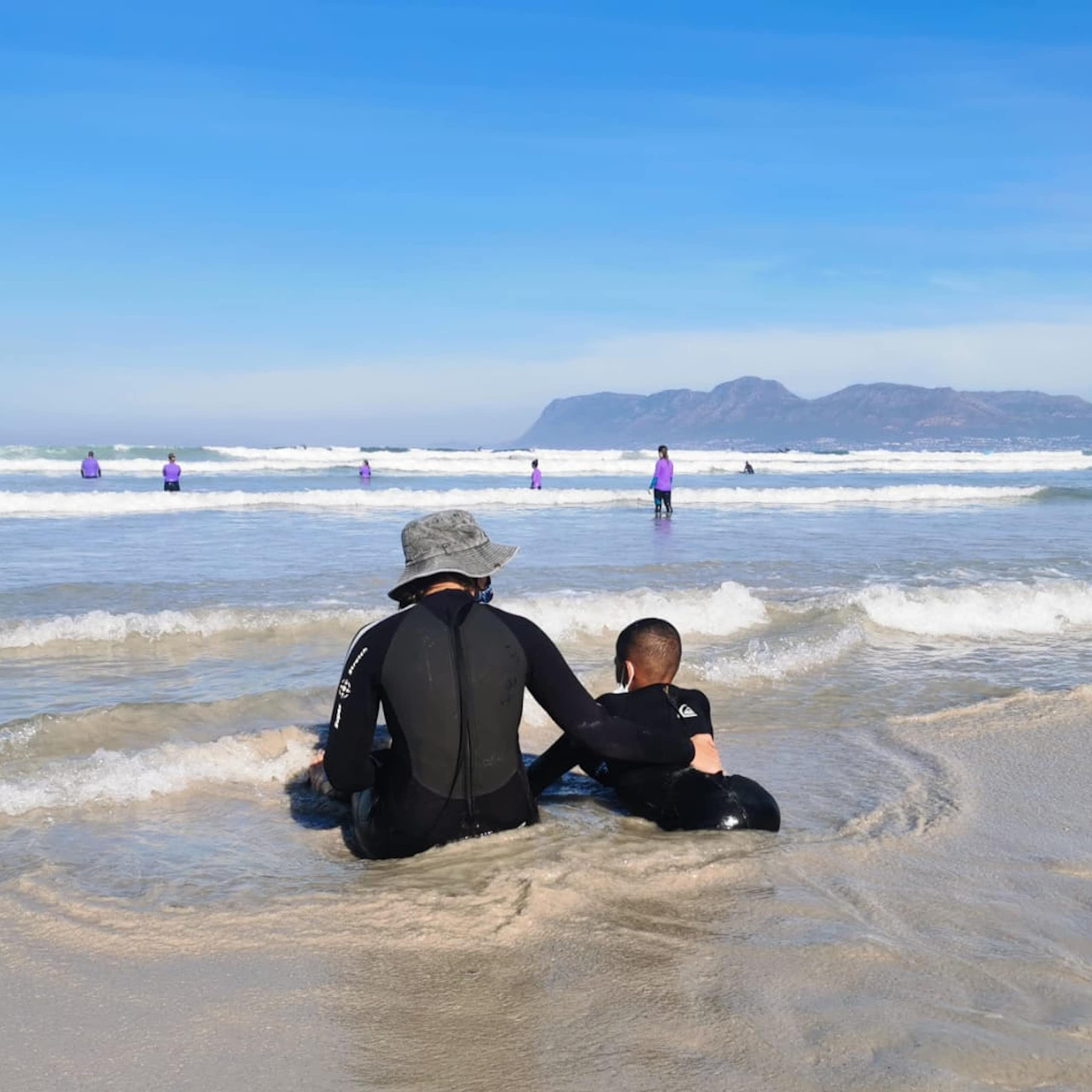 Child and adult sitting in the sea.