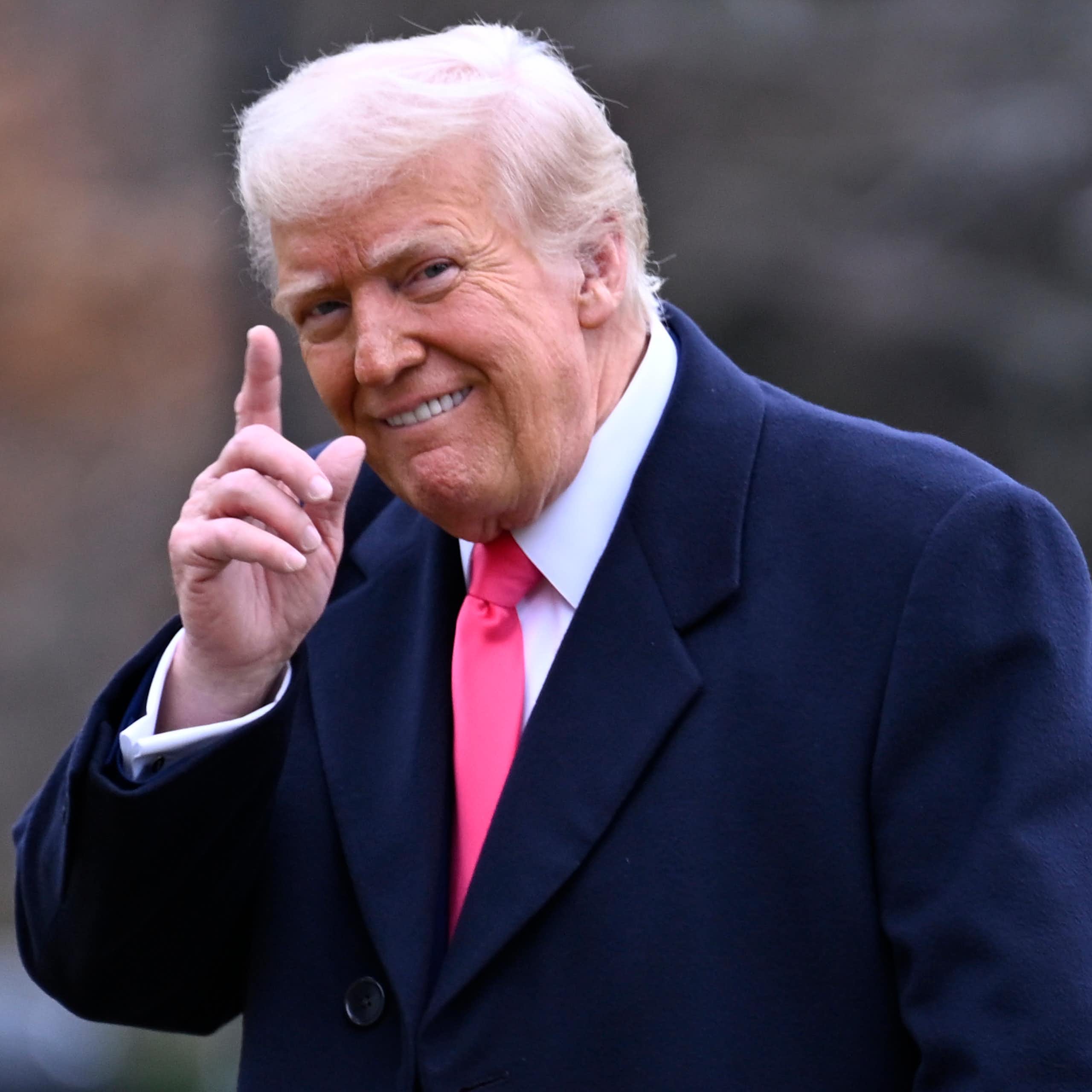 Un homme sourit en levant un doigt.