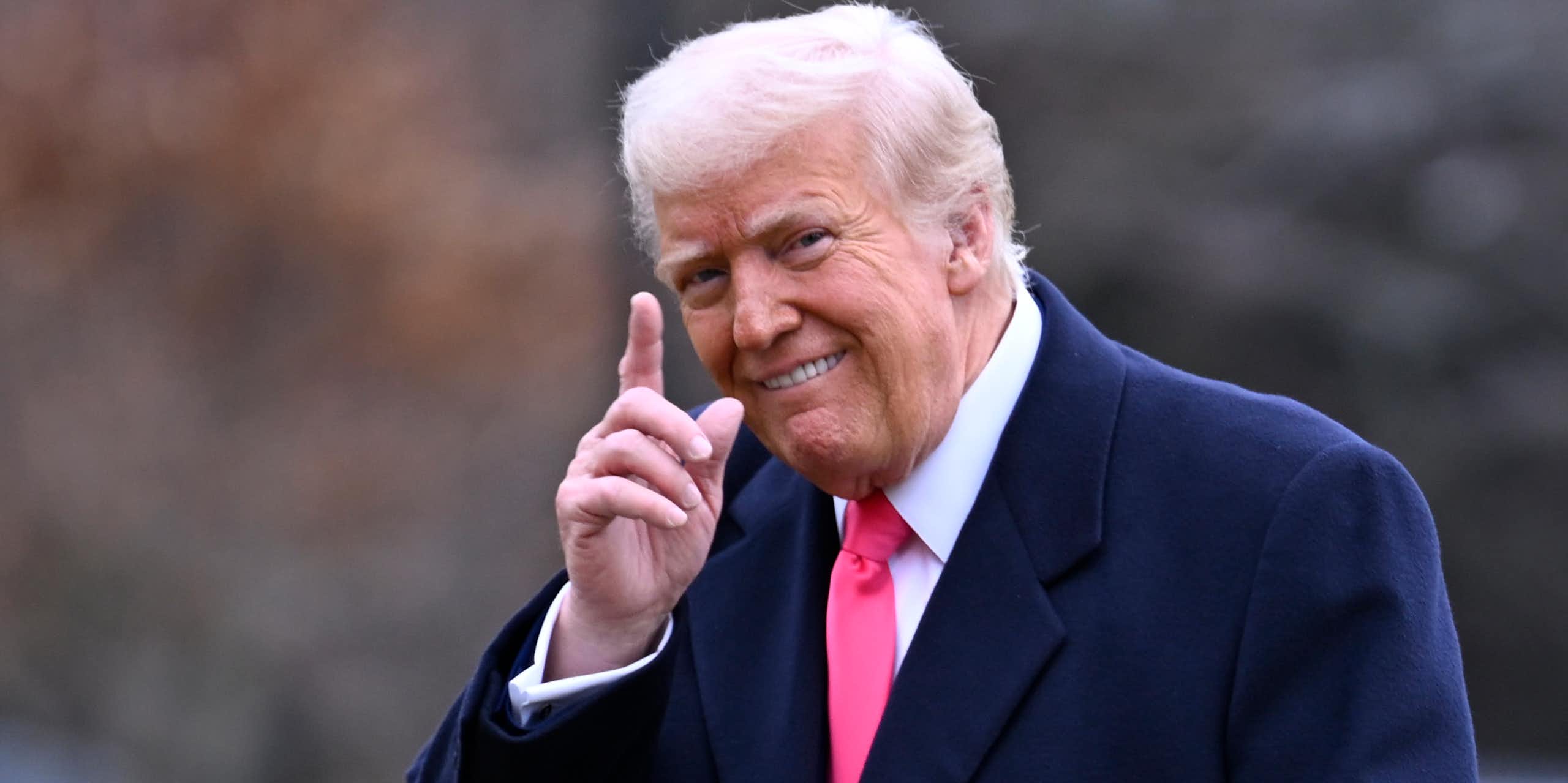 Un homme sourit en levant un doigt.