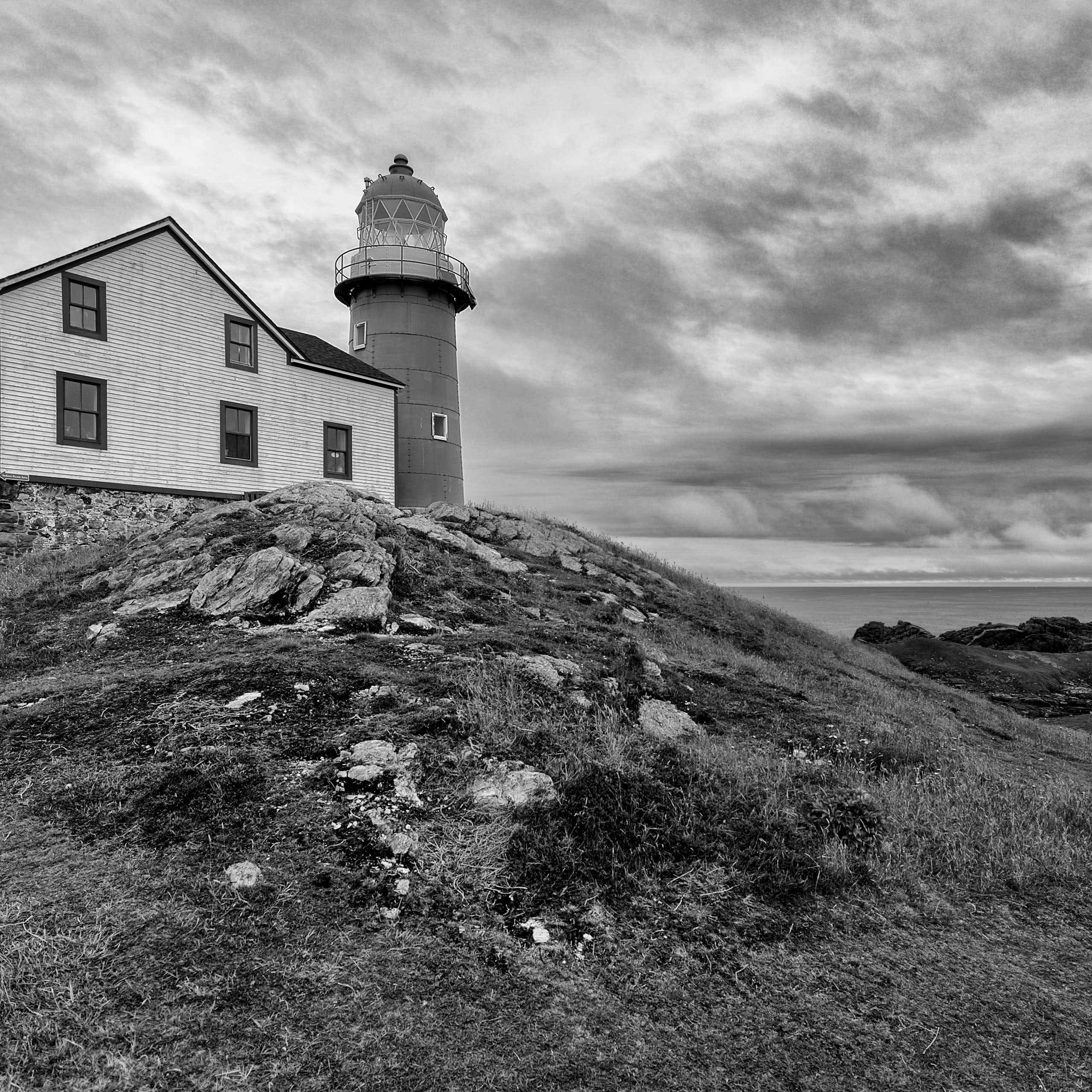 hut and lighthouse, by the coast, black and white image