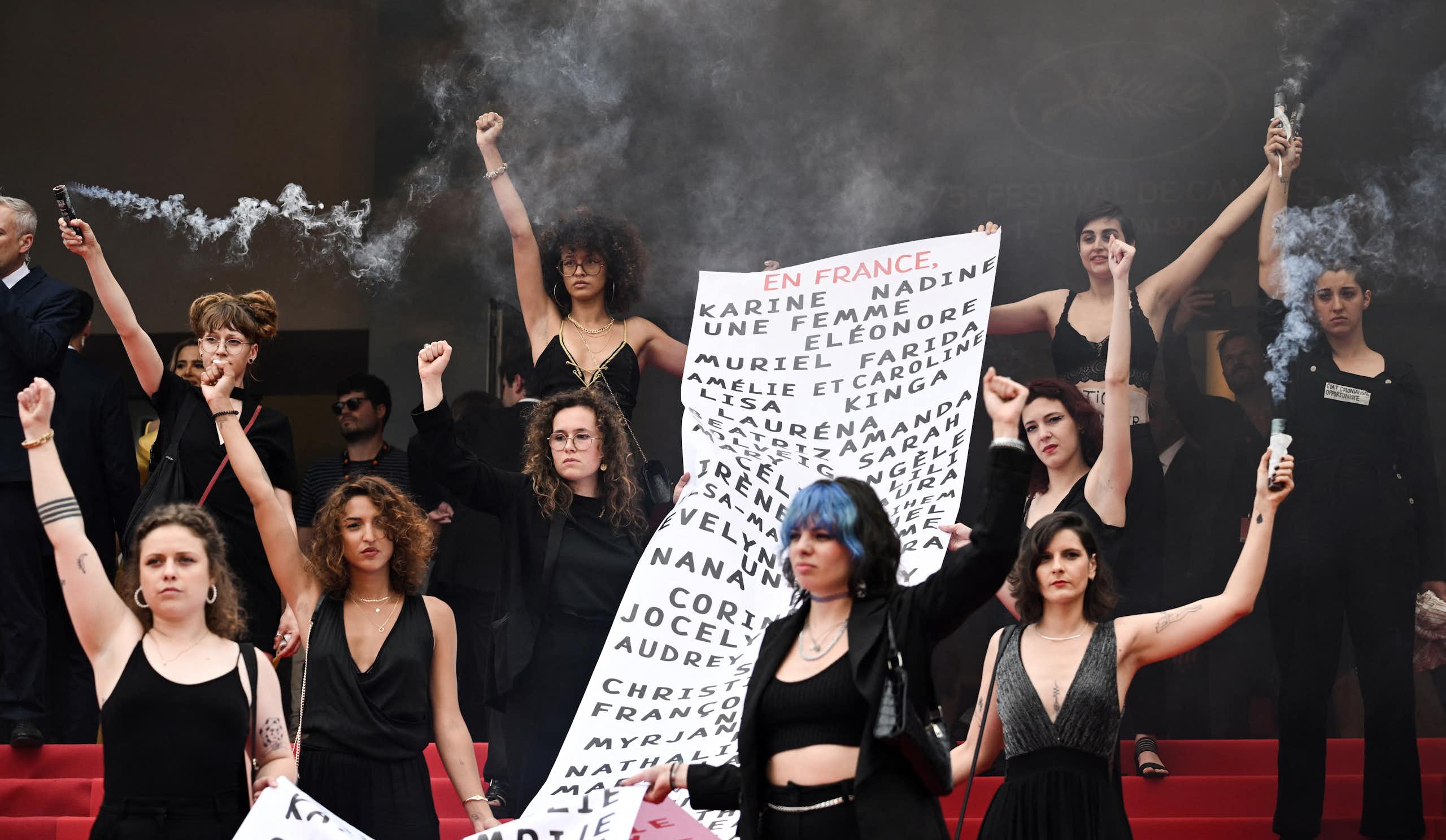 au Festival de Cannes en 2022, des membres du mouvement féministe « Les Colleuses » tiennent une banderole portant les noms de 129 victimes de féminicides.