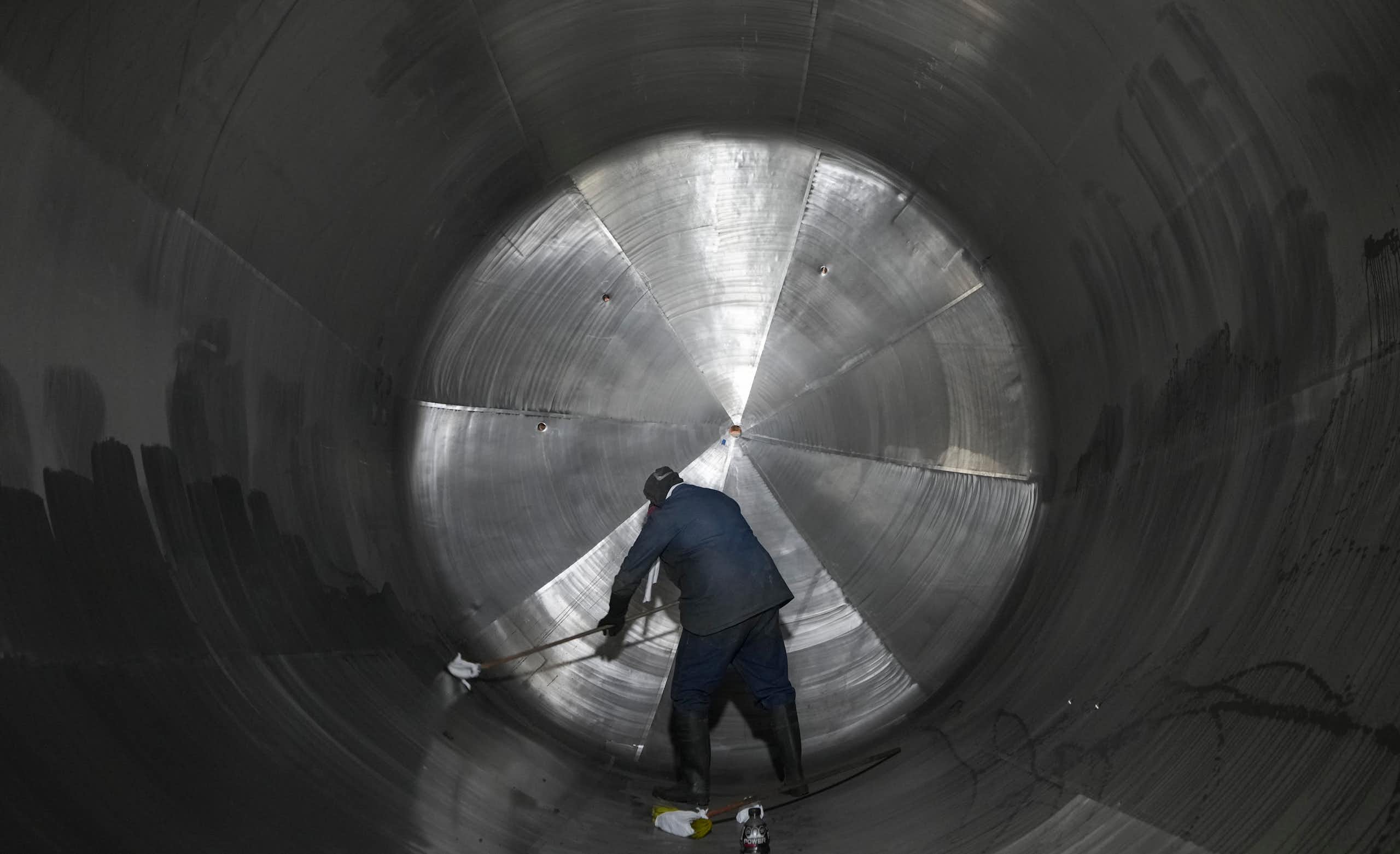 A man cleans the inside of a massive cylindrical steel tank