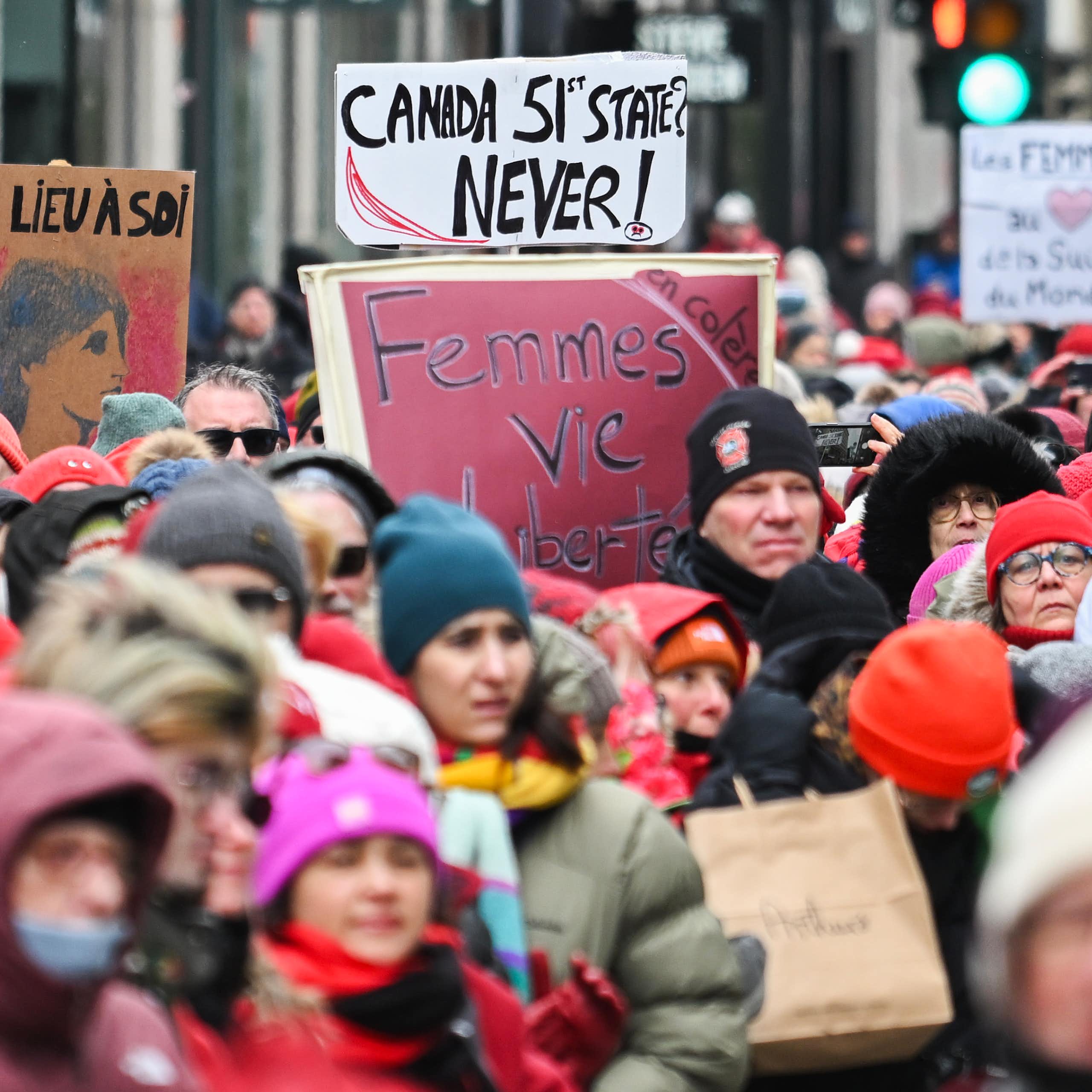 A crowd of people hold up signs, one reading Canada 51st State? Never!