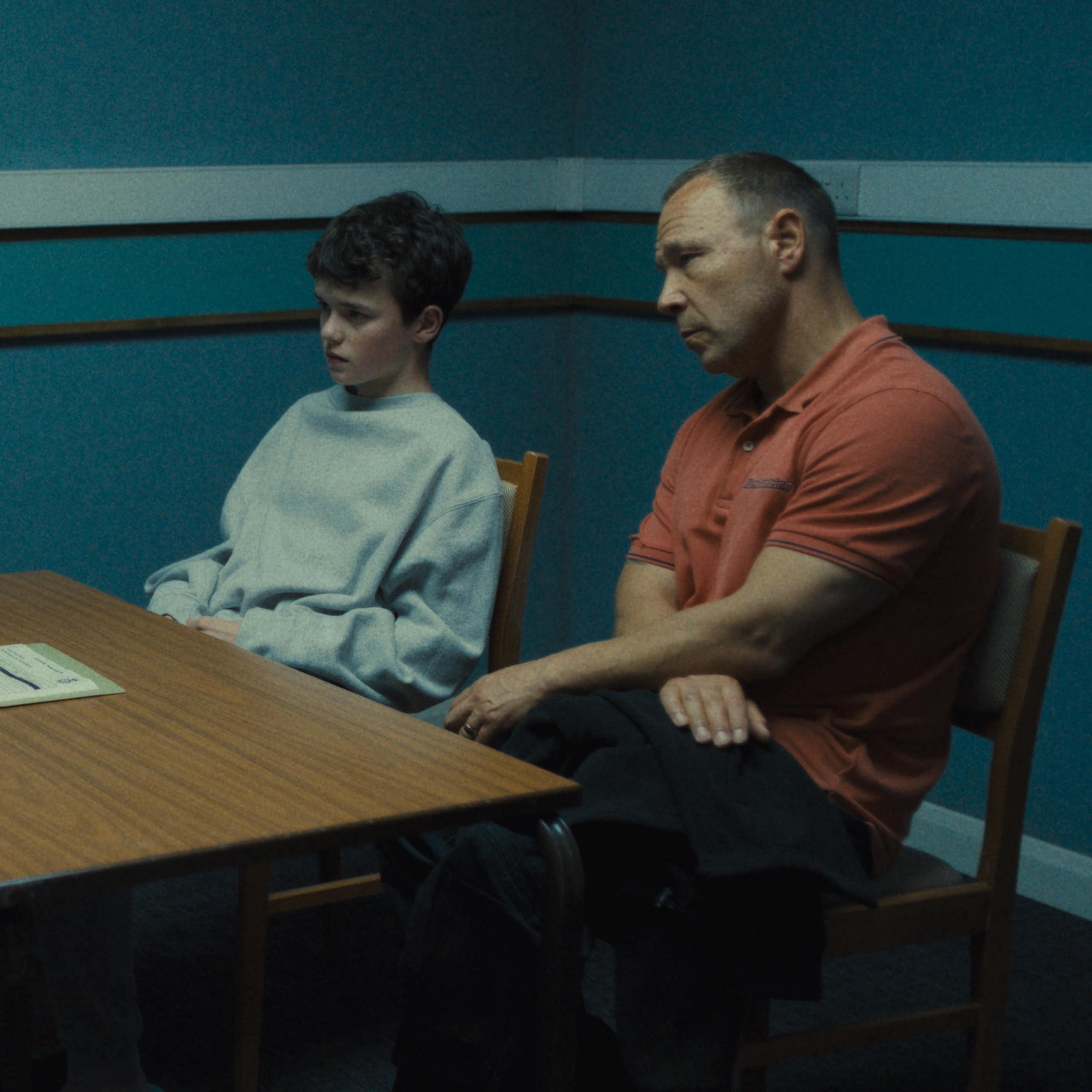 Um menino e seu pai sentaram-se em uma sala de interrogatório com um detetive