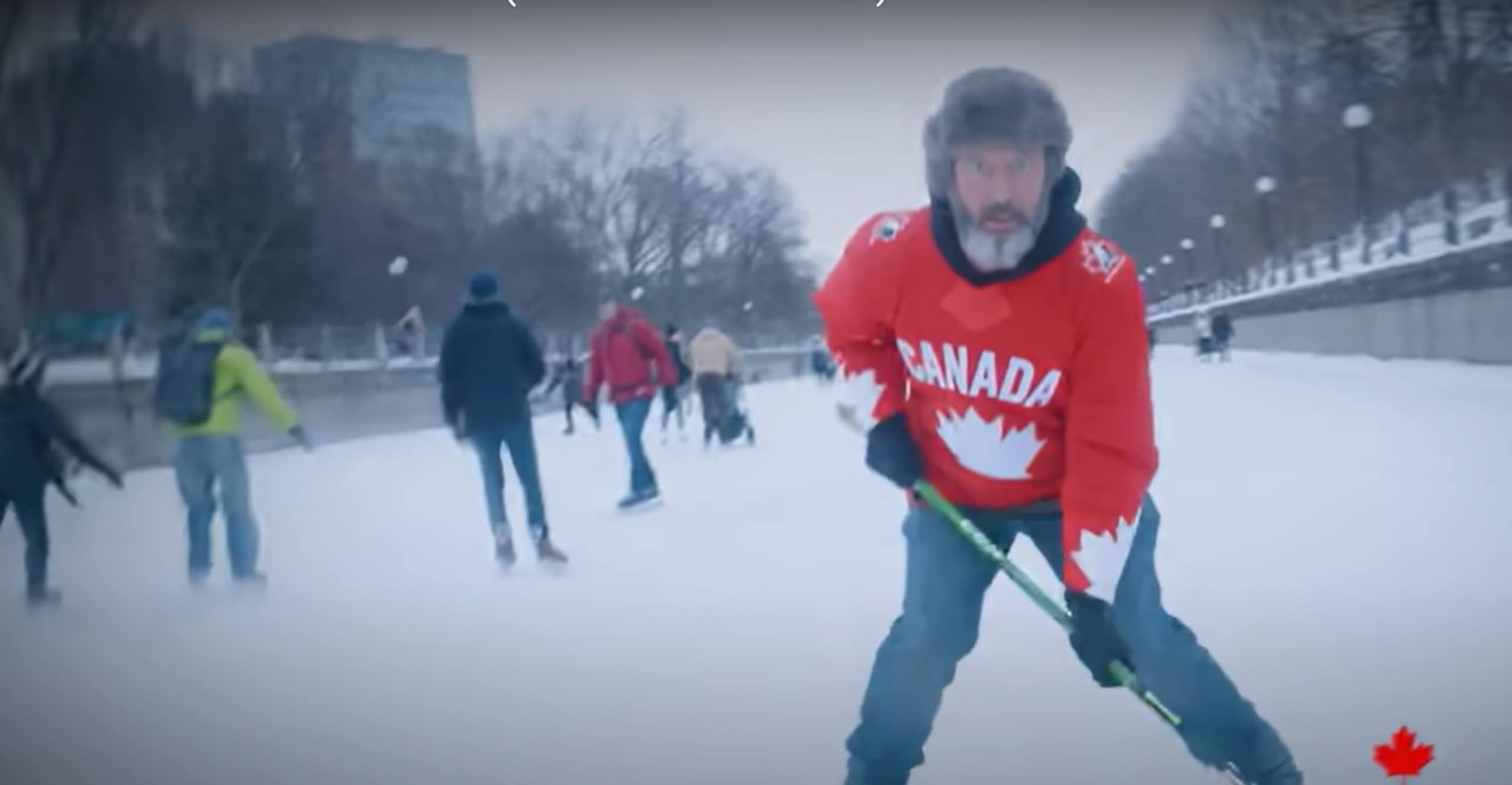 A man in fur hat with a Canada hockey sweater and a hockey stick skating.