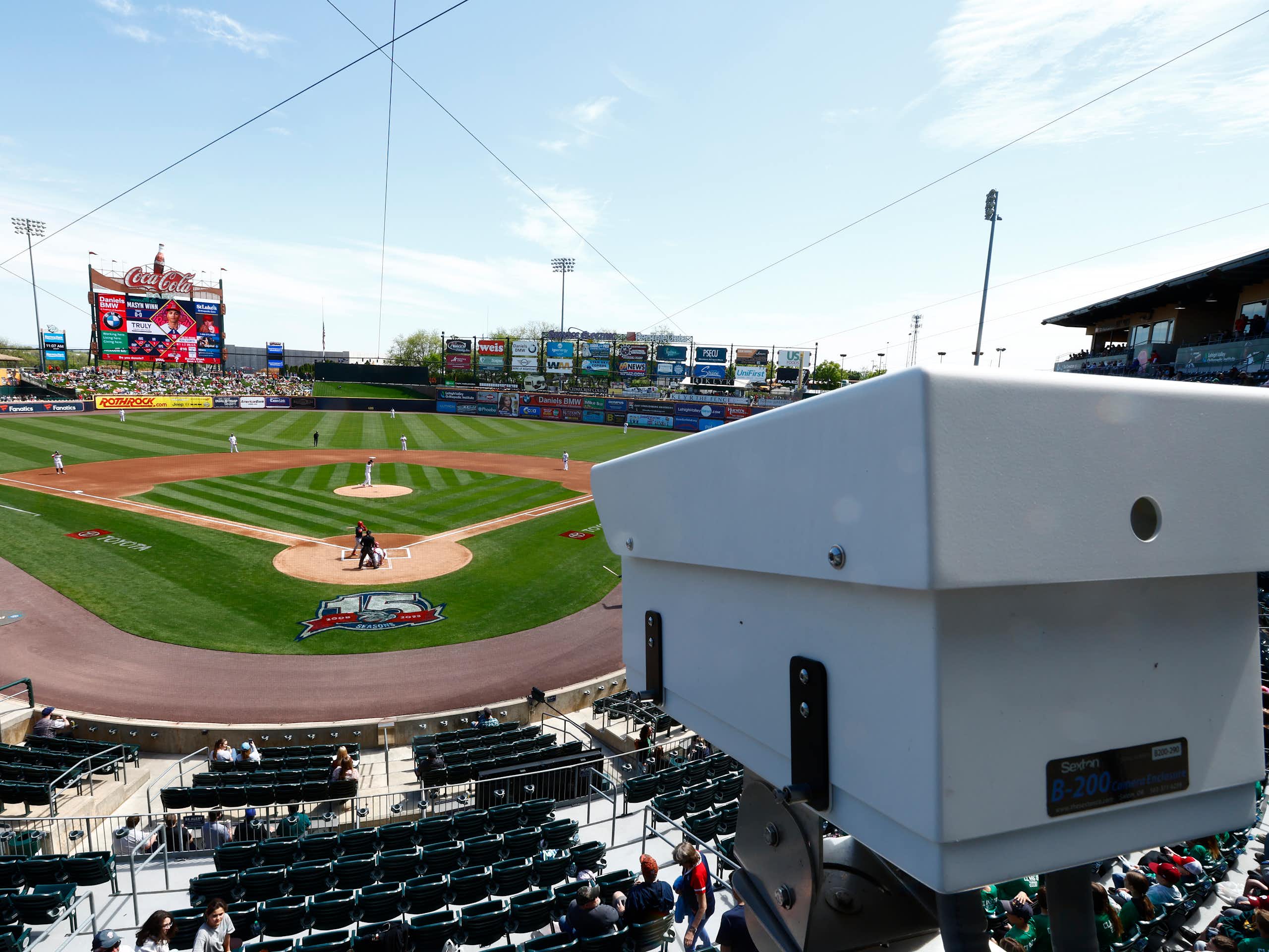 A white camera installed in a baseball stadium overlooking the field.