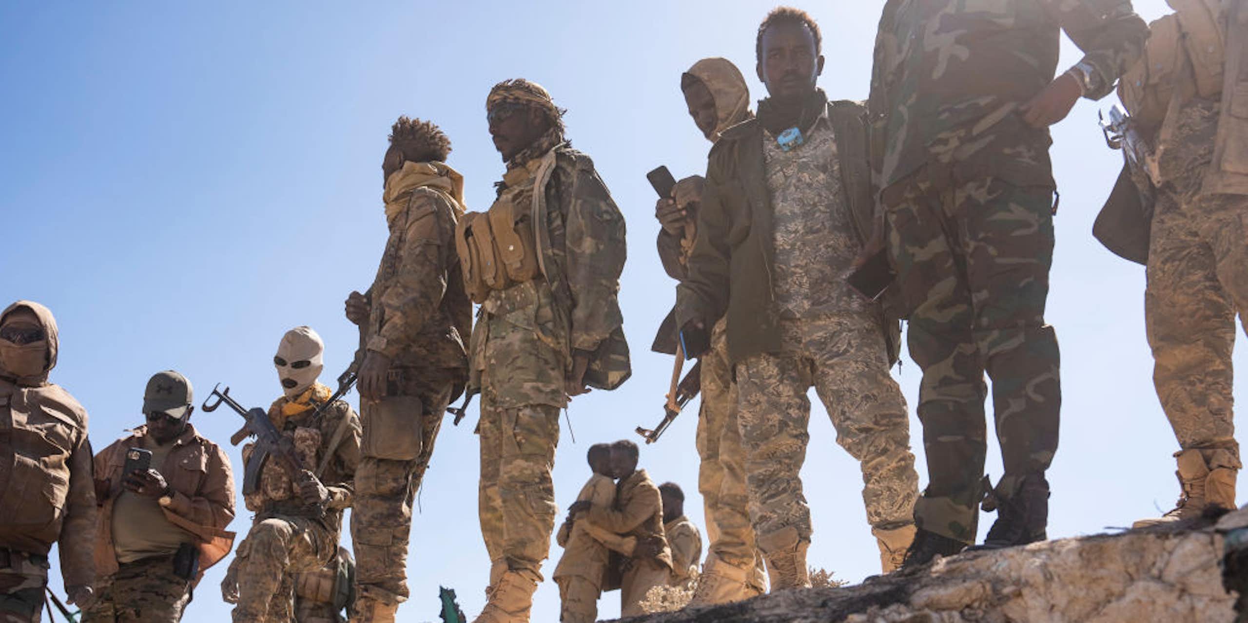 Men in combat uniforms, carrying weapons
