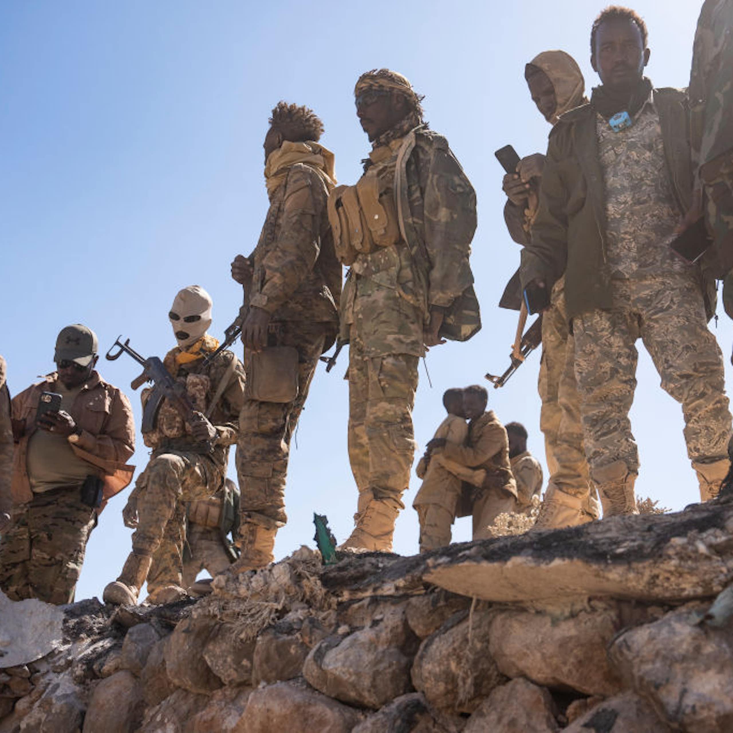 Men in combat uniforms, carrying weapons