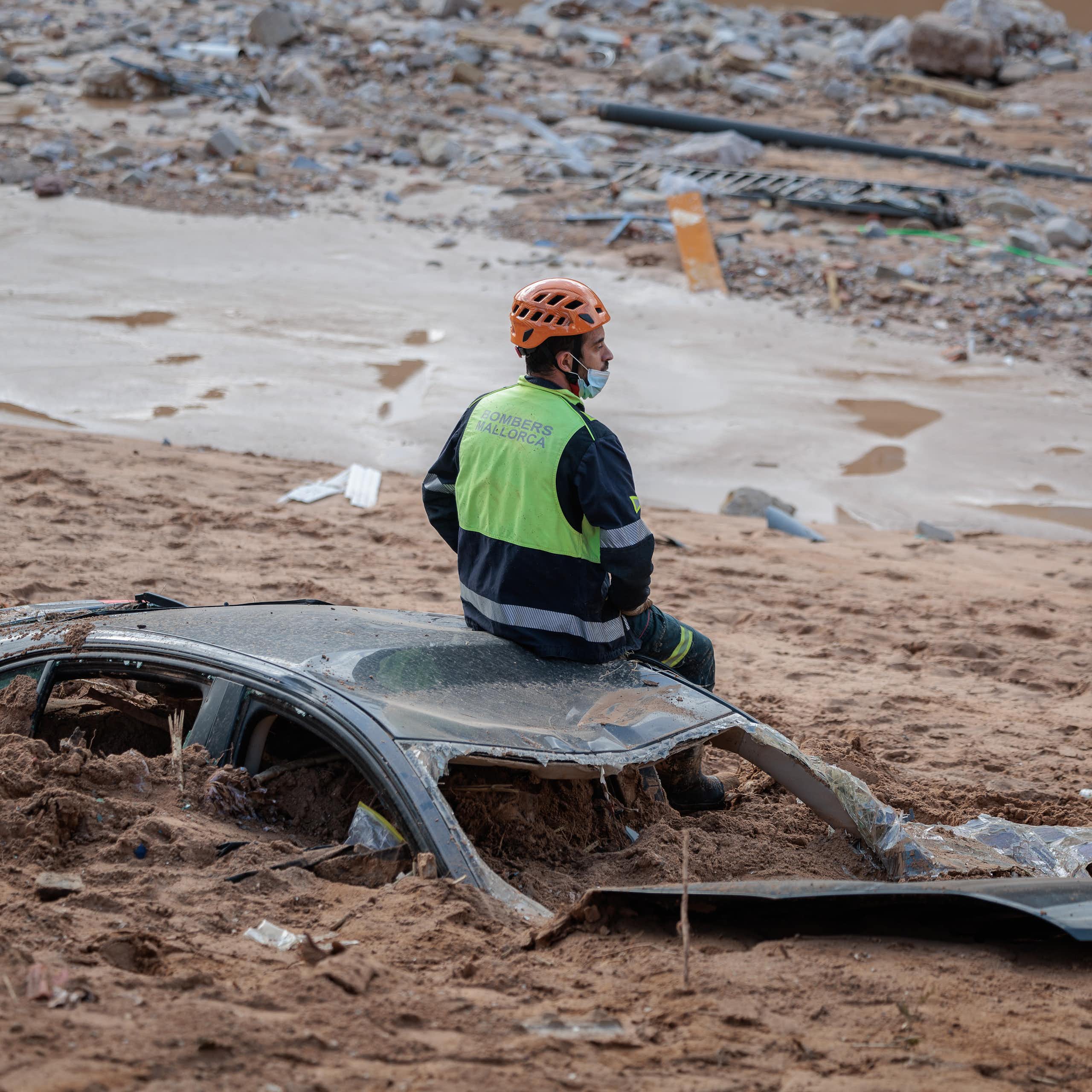 man sitting on car buried in mud.