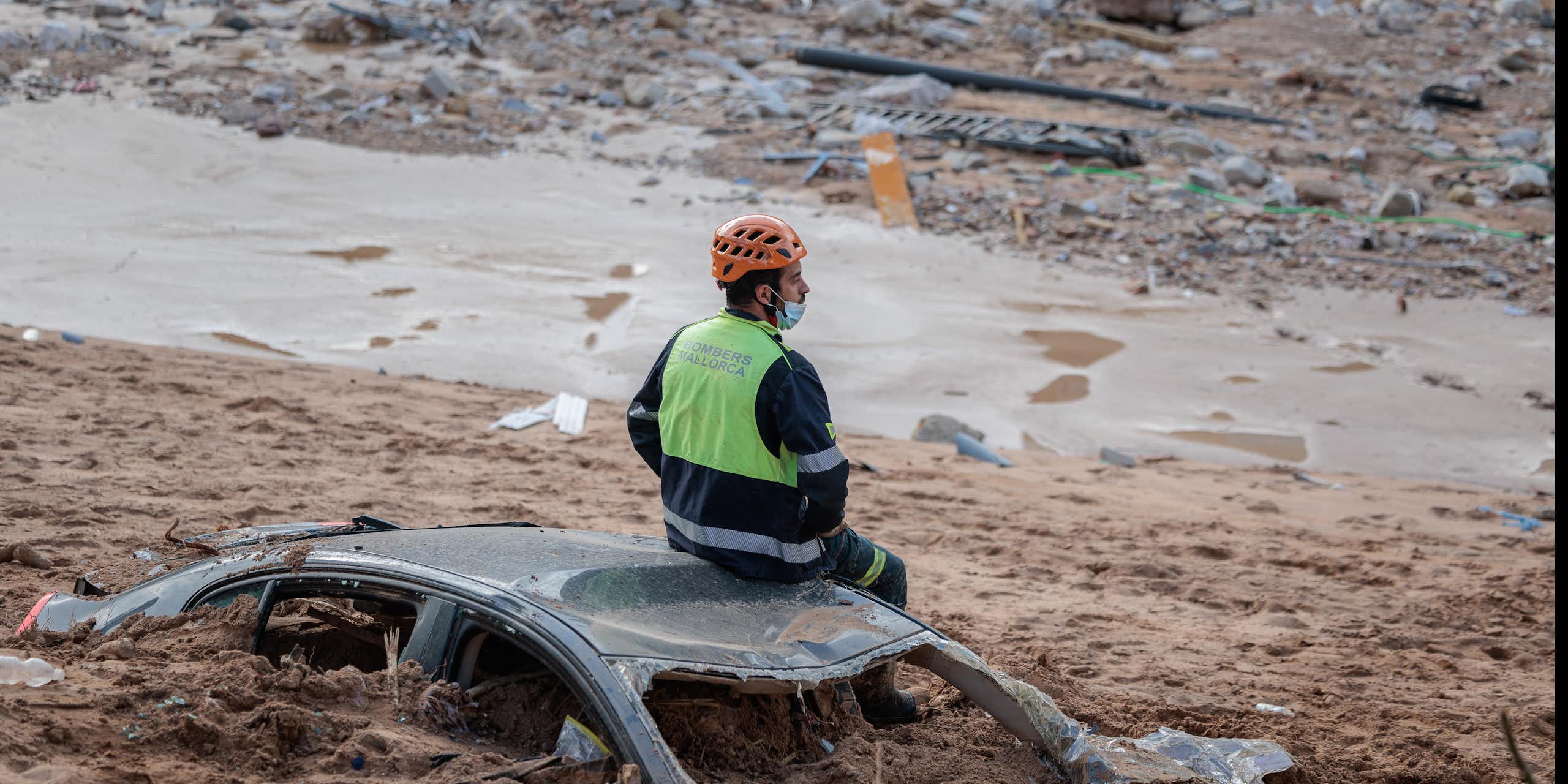 man sitting on car buried in mud.