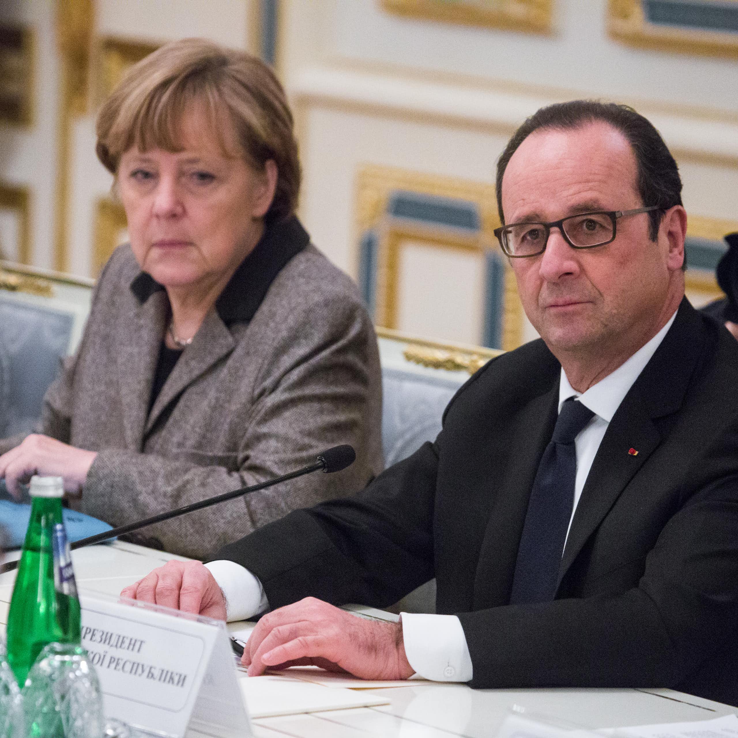 Angela Merkel and François Hollande sat next to each other at a table.