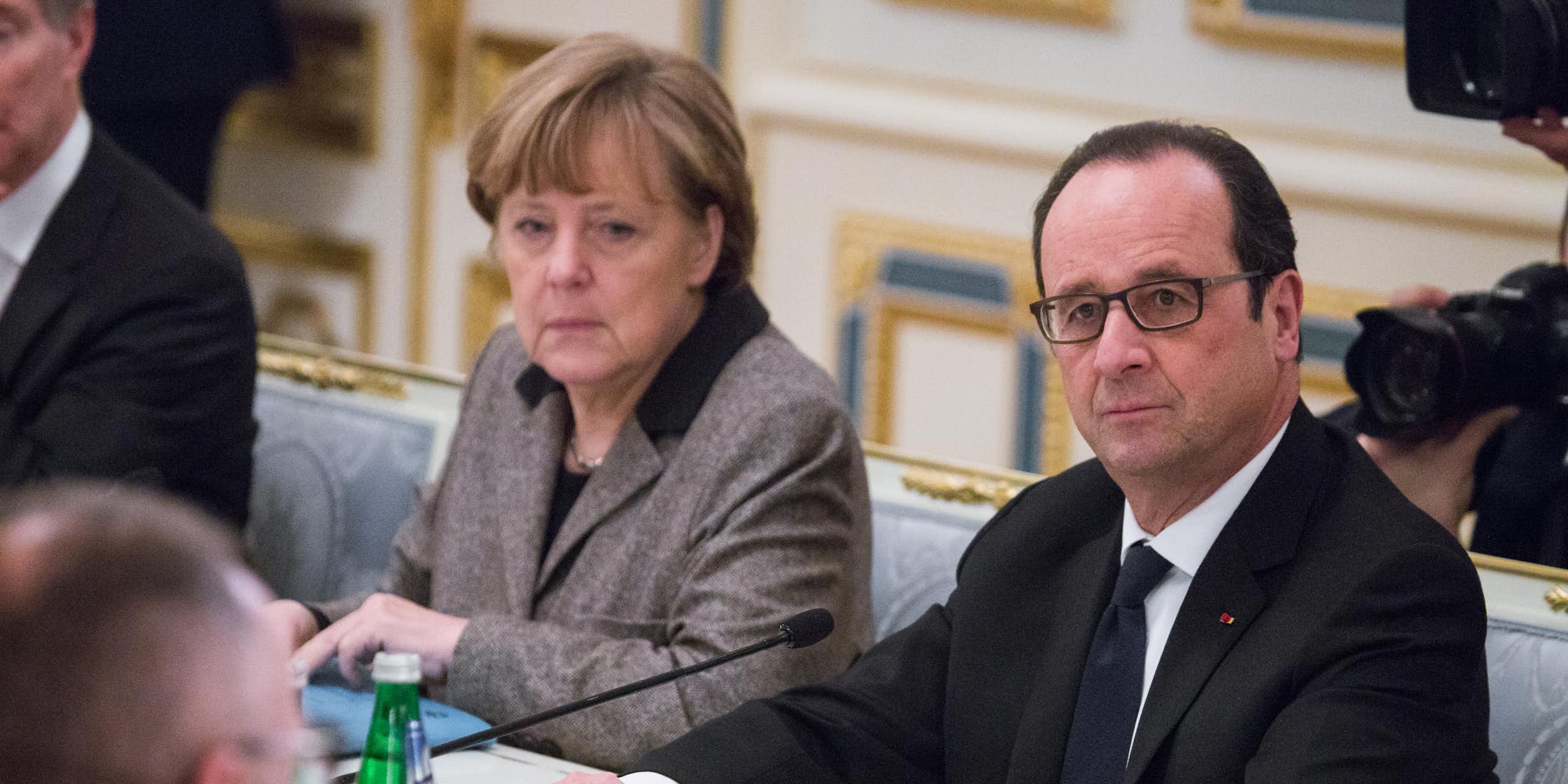 Angela Merkel and François Hollande sat next to each other at a table.