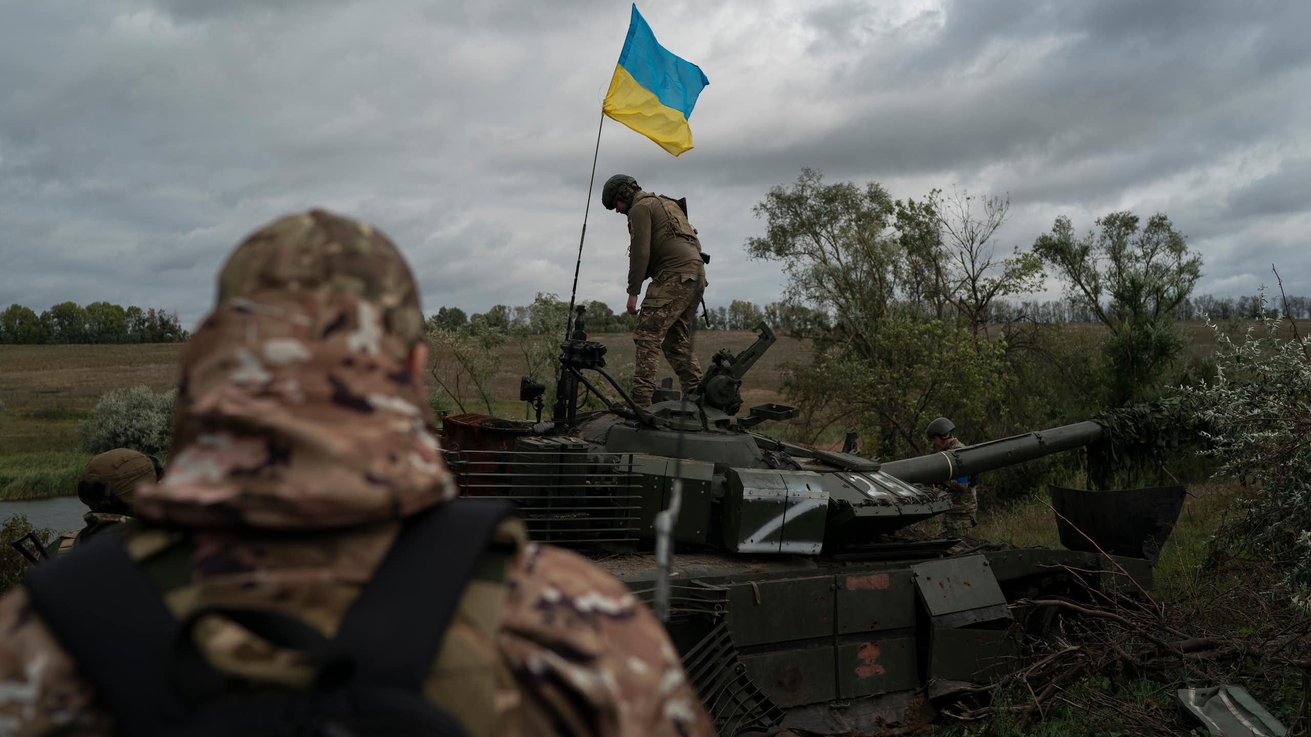 Un homme hisse un drapeau sur un char détruit.
