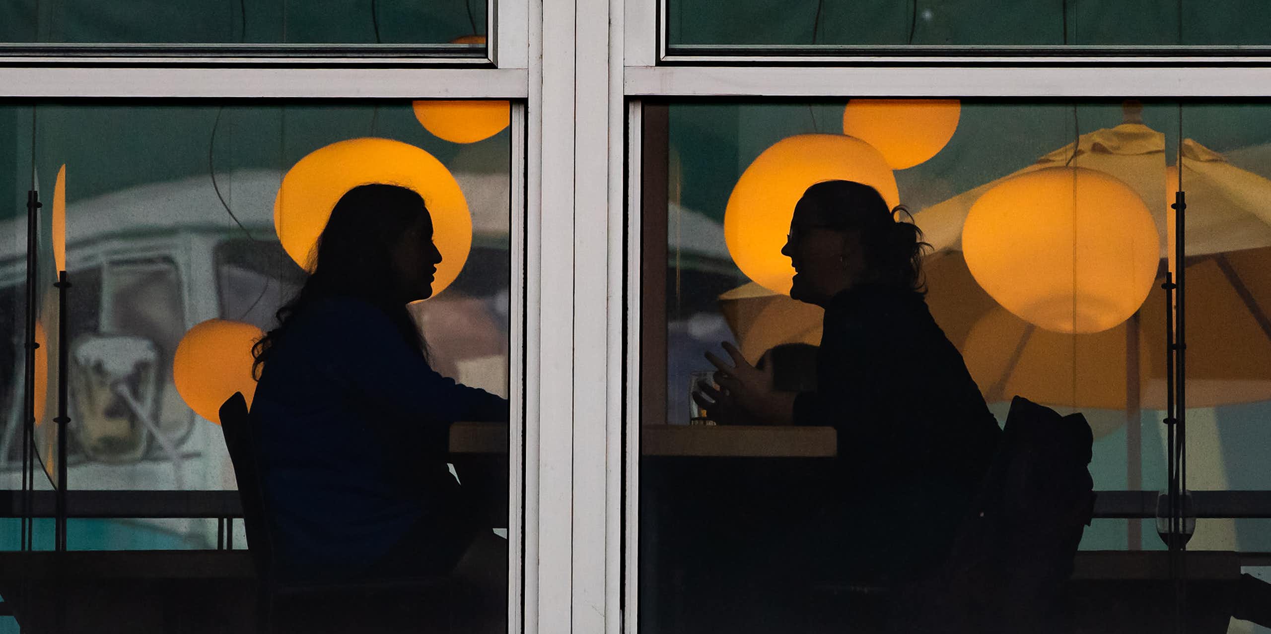 Two people are silhouetted while having a conversation.