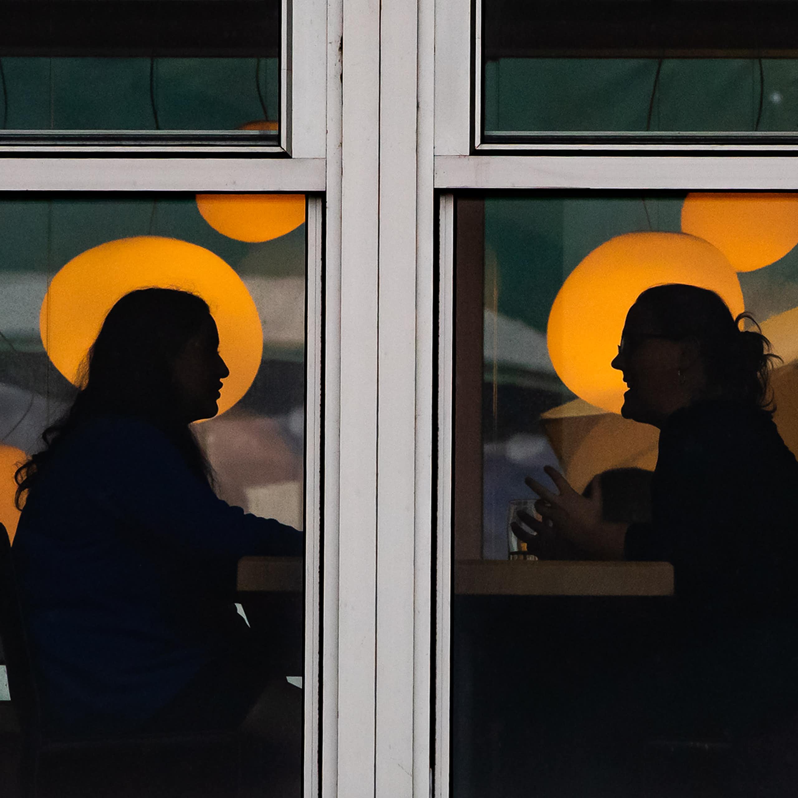 Two people are silhouetted while having a conversation.