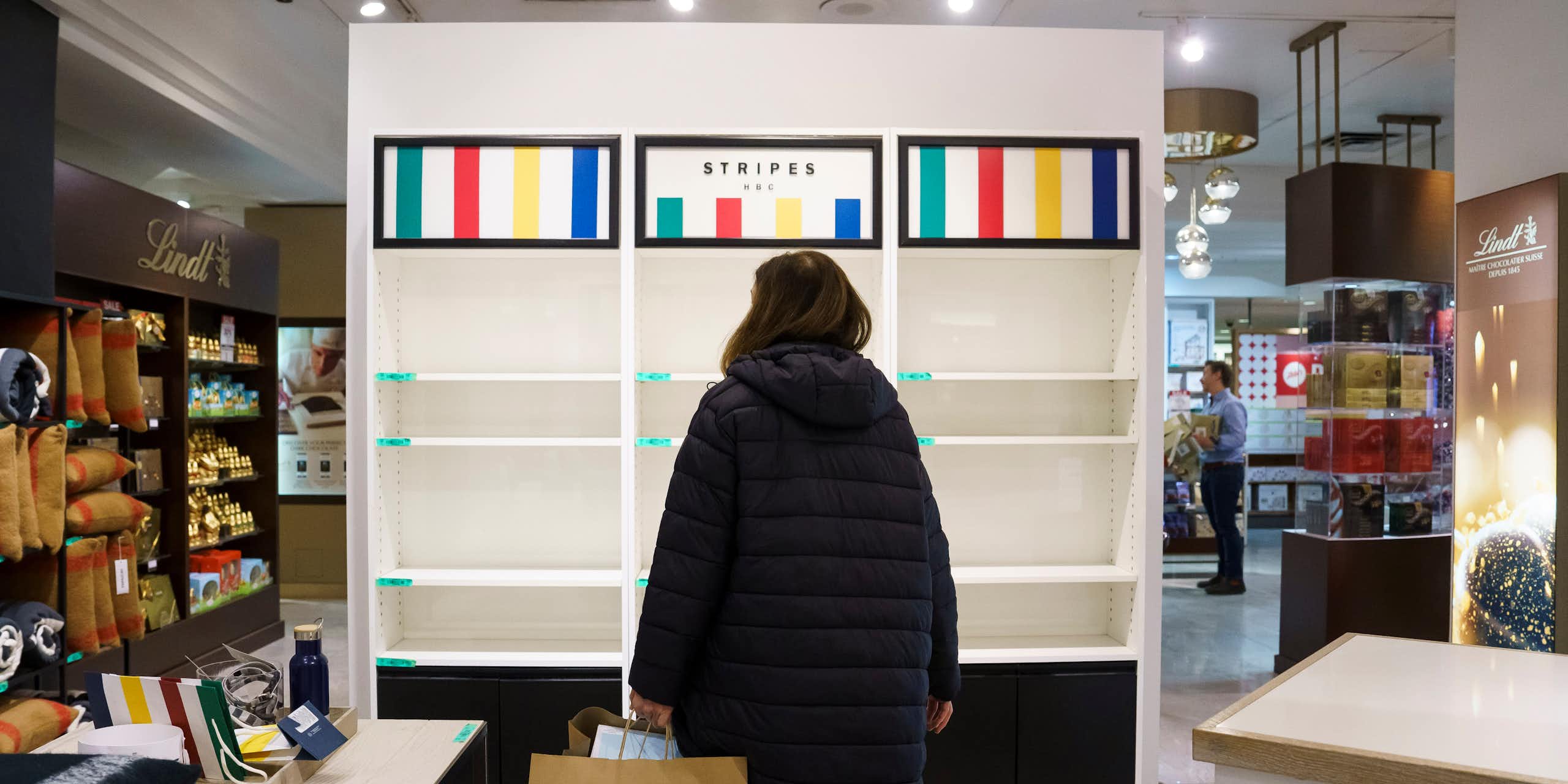 A woman, seen from behind, stands in front of empty shelves in a department store