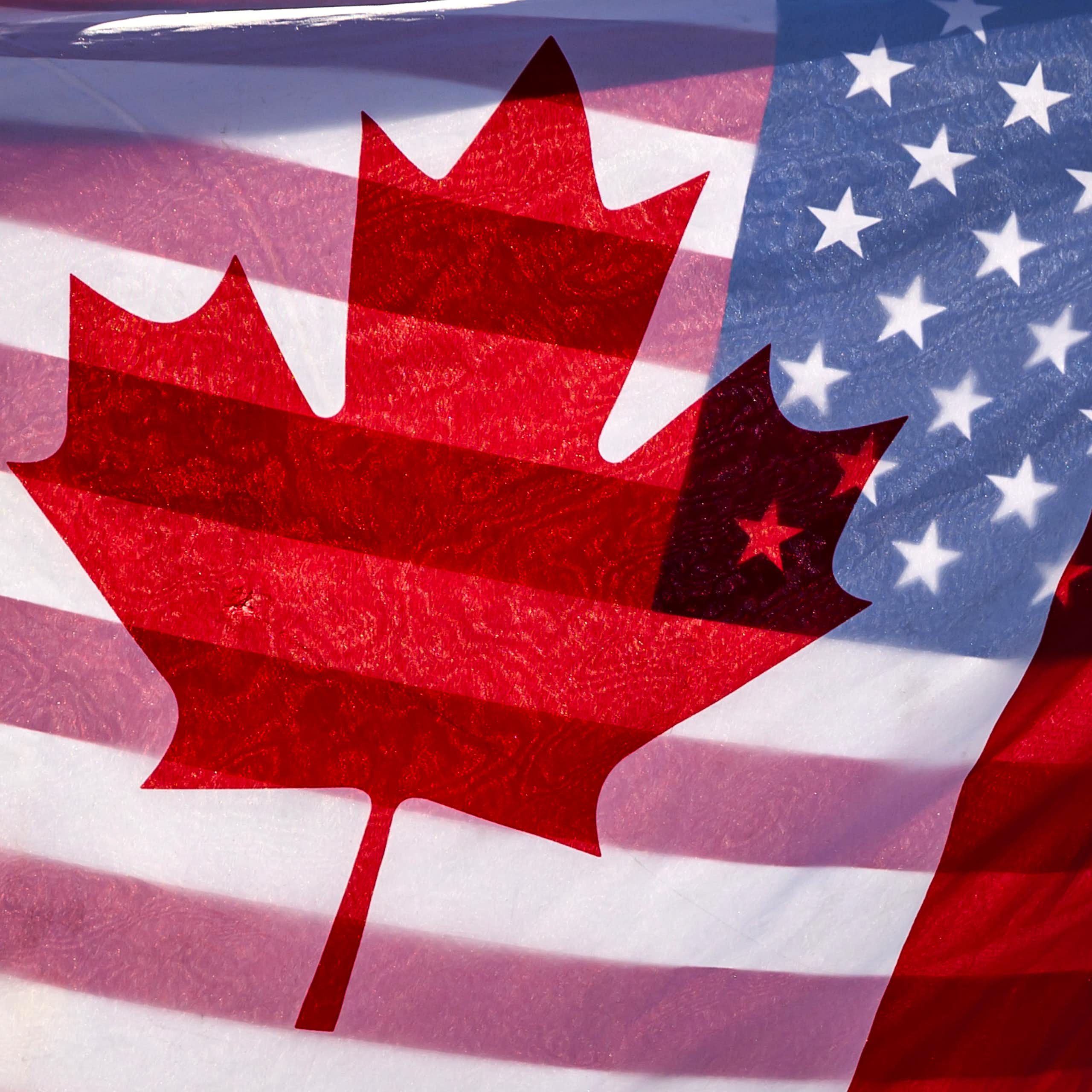 Sunlight shines through the flags of Canada and the United States
