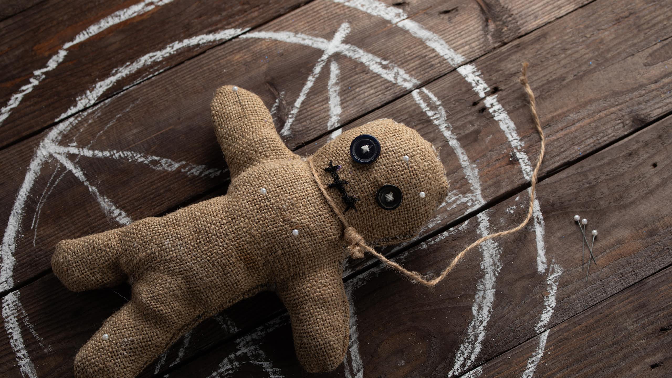 Muñeco vudú sobre una tabla de madera.